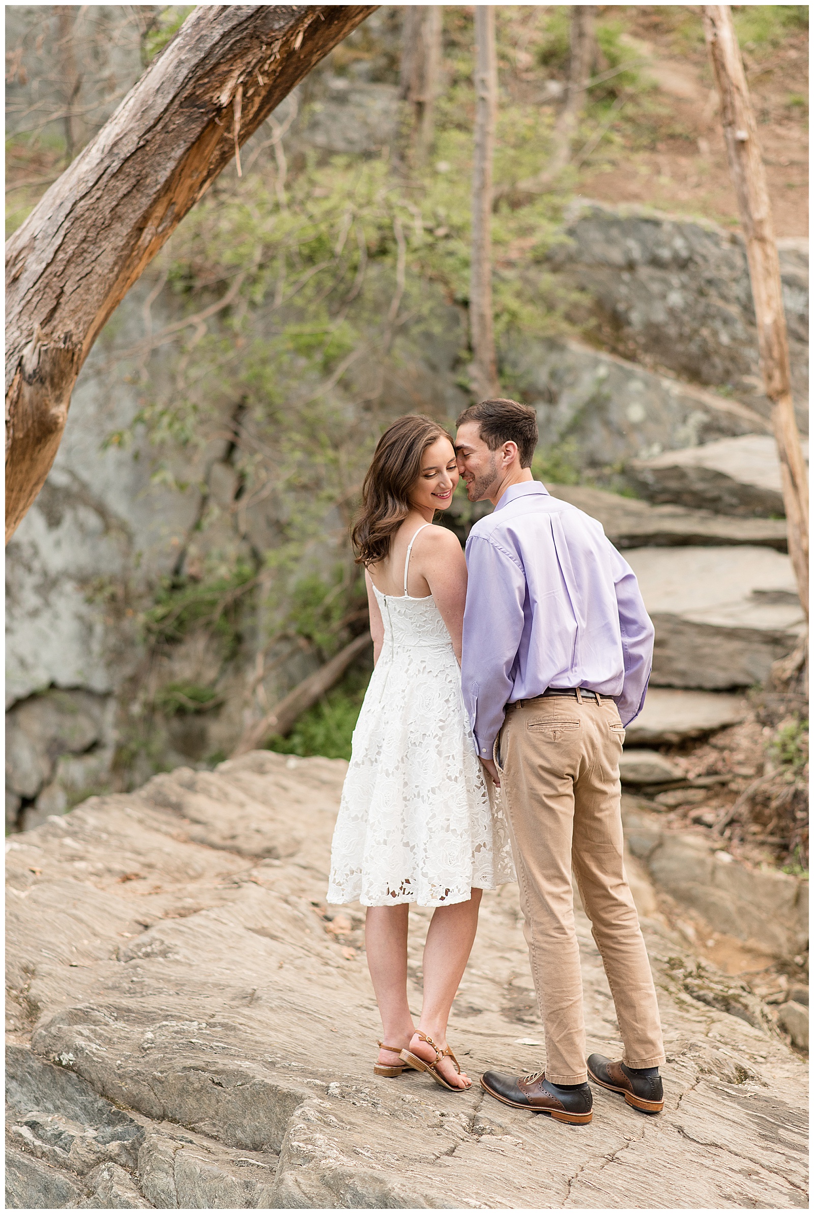 bride to be looking over right shoulder as guy kisses her left temple at rocks state park
