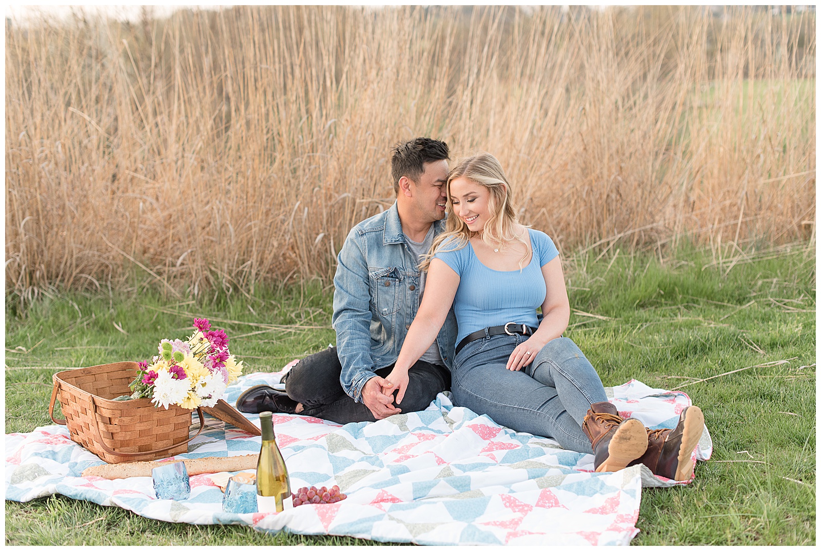 couple snuggles looking away from camera among picnic setting by tall grasses at overlook park