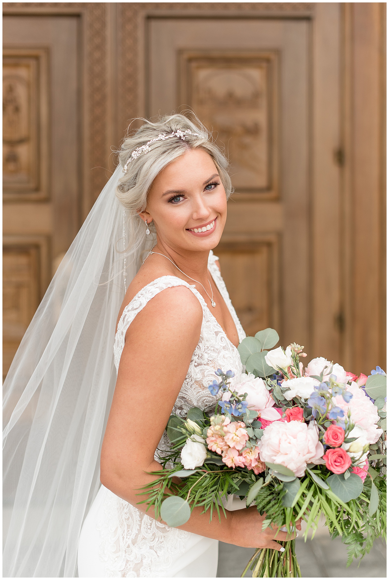 bride smiling looking over right shoulder with long veil and holding beautiful spring flower bouquet in maryland