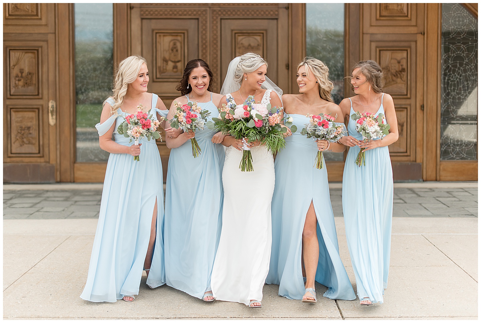 bride and bridesmaids walking towards camera smiling and looking at each other holding bouquets in maryland