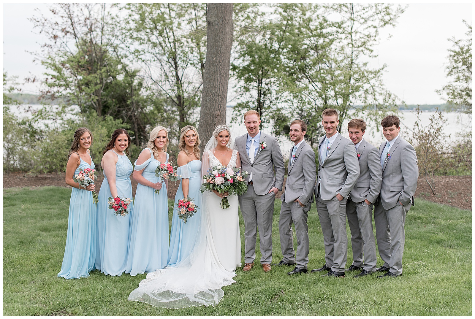 bride and groom with bridal party on grass lawn by large trees in forest hills maryland