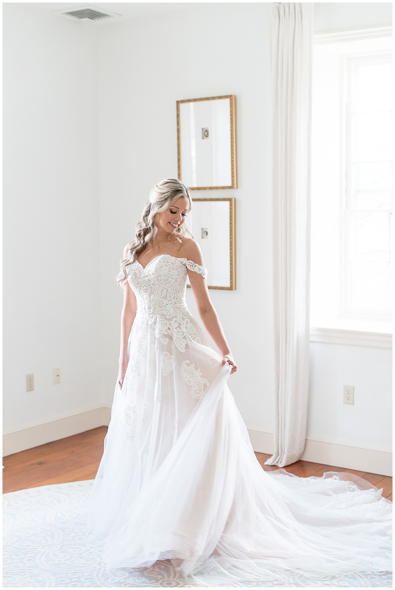 bride looking over left shoulder fanning out wedding gown train and smiling in bridal suite in lancaster pennsylvania