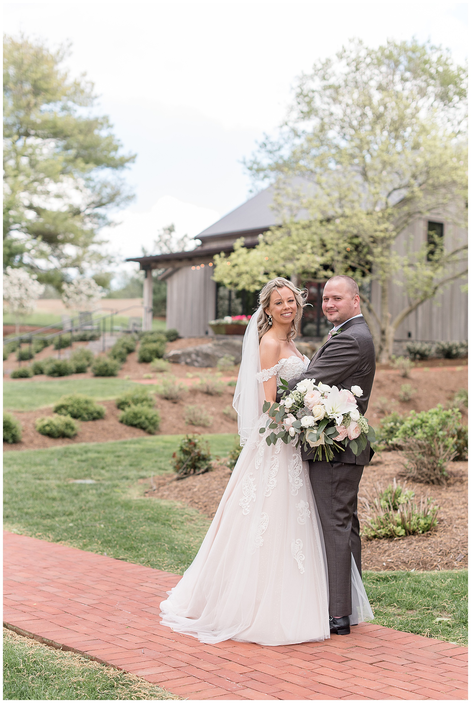 bride and groom smiling in landscaped yard at the farm at eagles ridge in lancaster pennsylvania