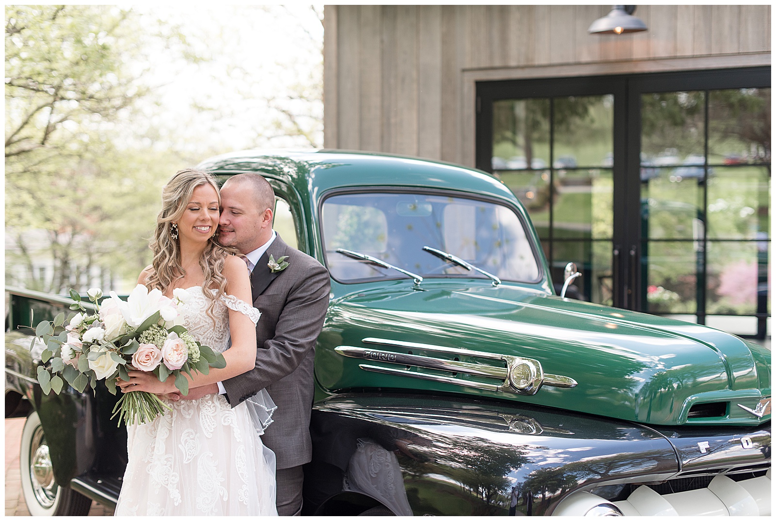 bride and groom leaning back against vintage truck hugging and smiling on sunny spring day at the farm at eagles ridge