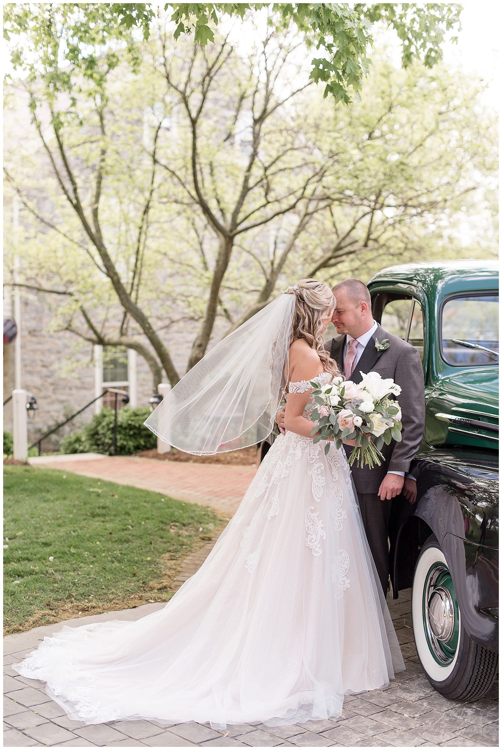 bride's white train displayed behind her as she rests her forehead against groom's forehead beside vintage truck in lancaster pennsylvania