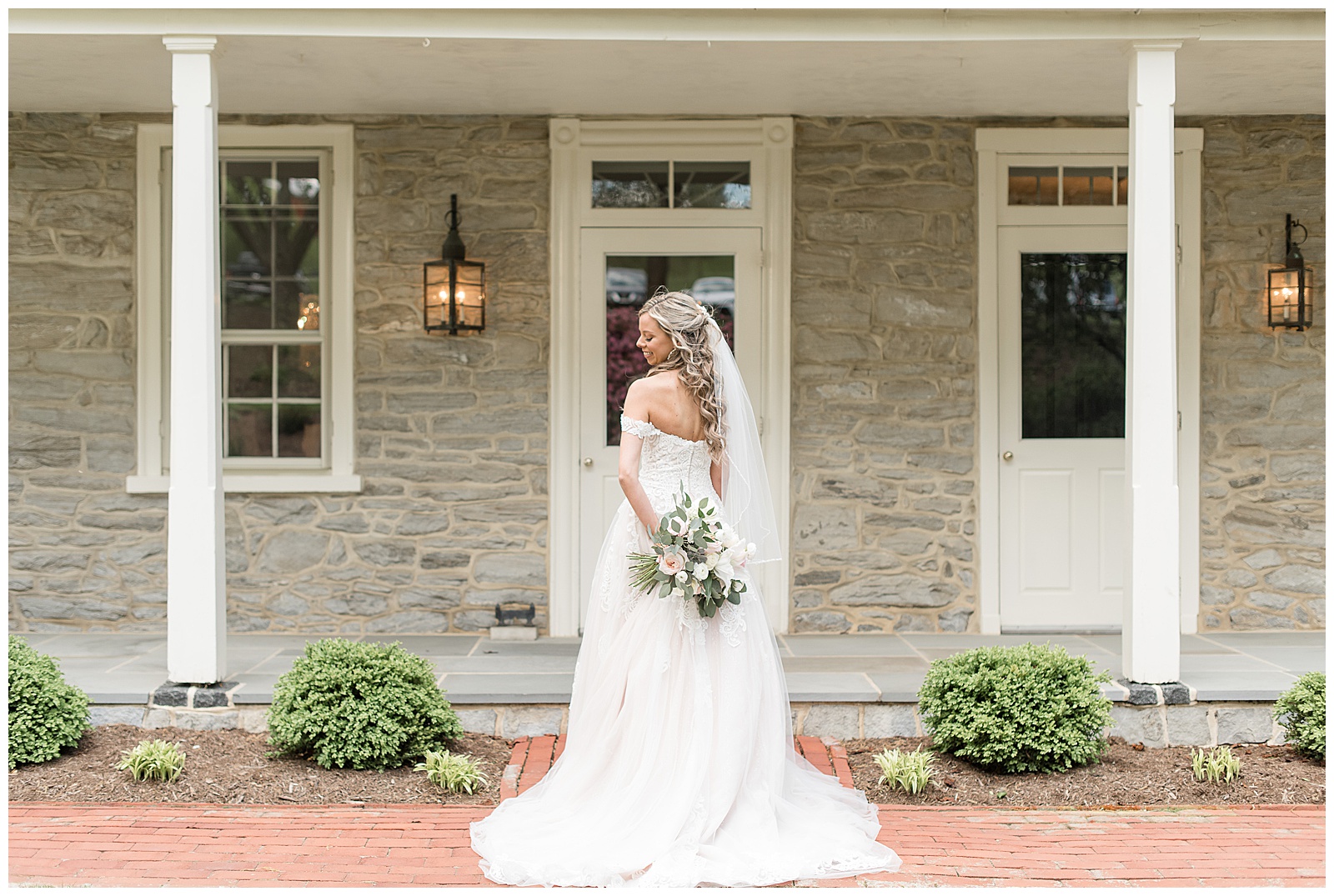 bride's back to camera as she holds stunning bouquet behind her glancing over left shoulder outside farmhouse at the farm at eagles ridge