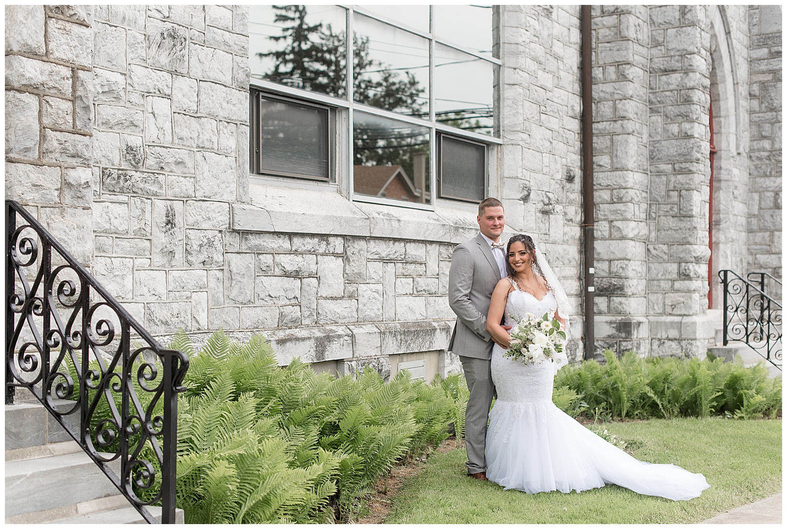 groom in gray suit standing behind bride in white mermaid wedding gown hugging her in columbia pennsylvania