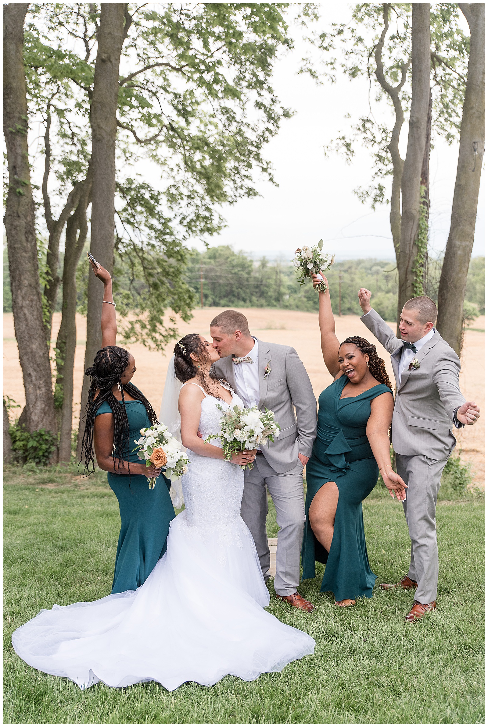 couple kissing as wedding party surrounds them cheering with arms held high in beautiful columbia pennsylvania