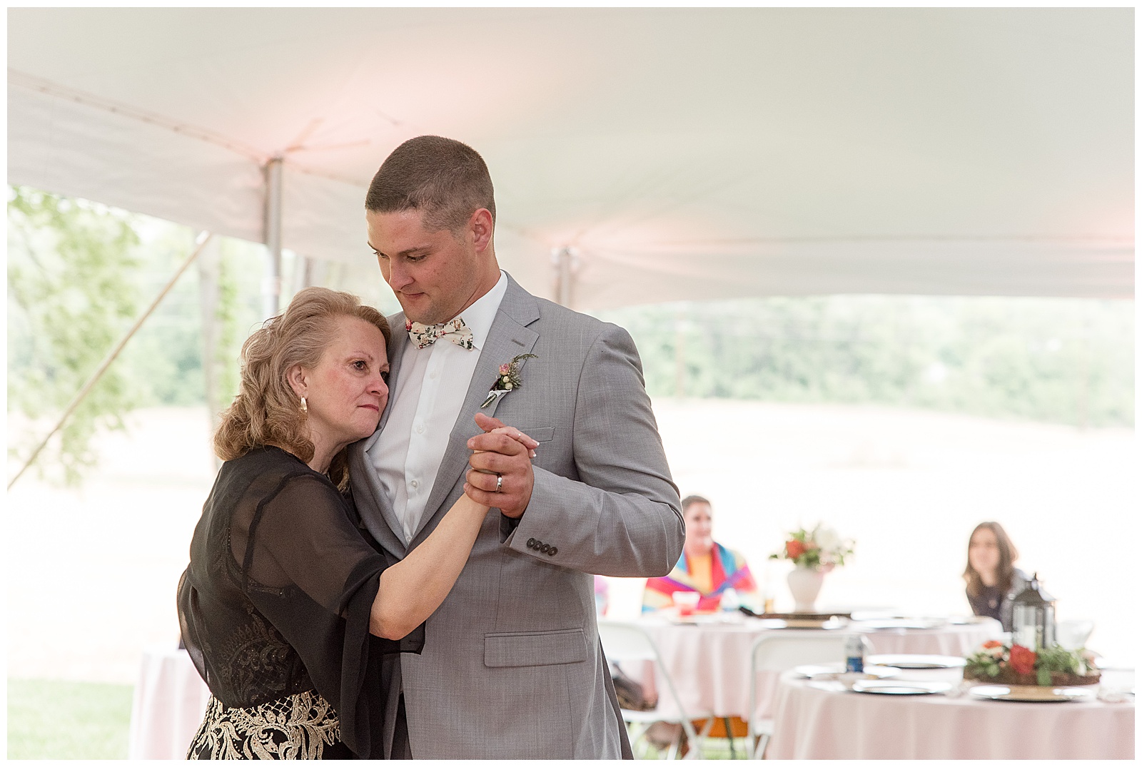 groom slow dancing with his mom and hugging her tightly as she rests her left cheek against him