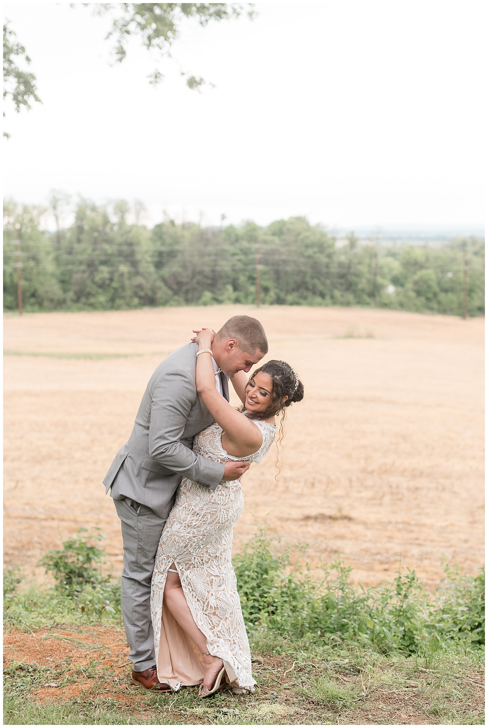 groom dips bride backwards as he looks at her and she looks down near field in columbia pennsylvania