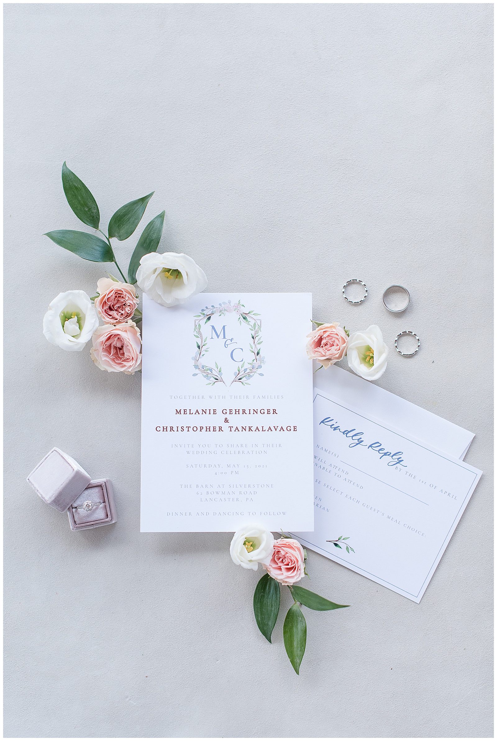 wedding invitation and wedding rings displayed with beautiful flowers placed around them on spring wedding day
