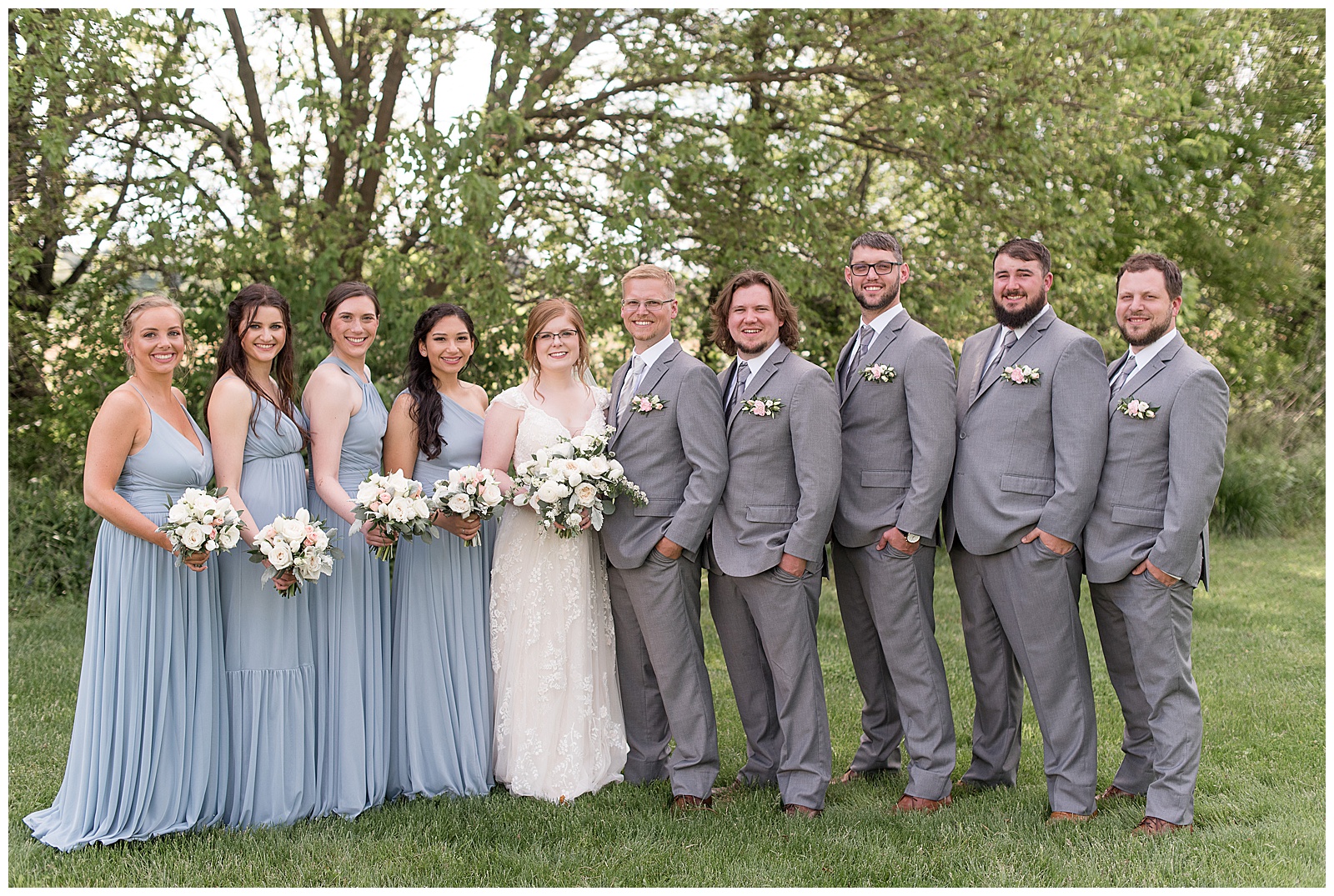 couple with bridal party and bridesmaids wearing light blue dresses and groomsmen wearing gray suits