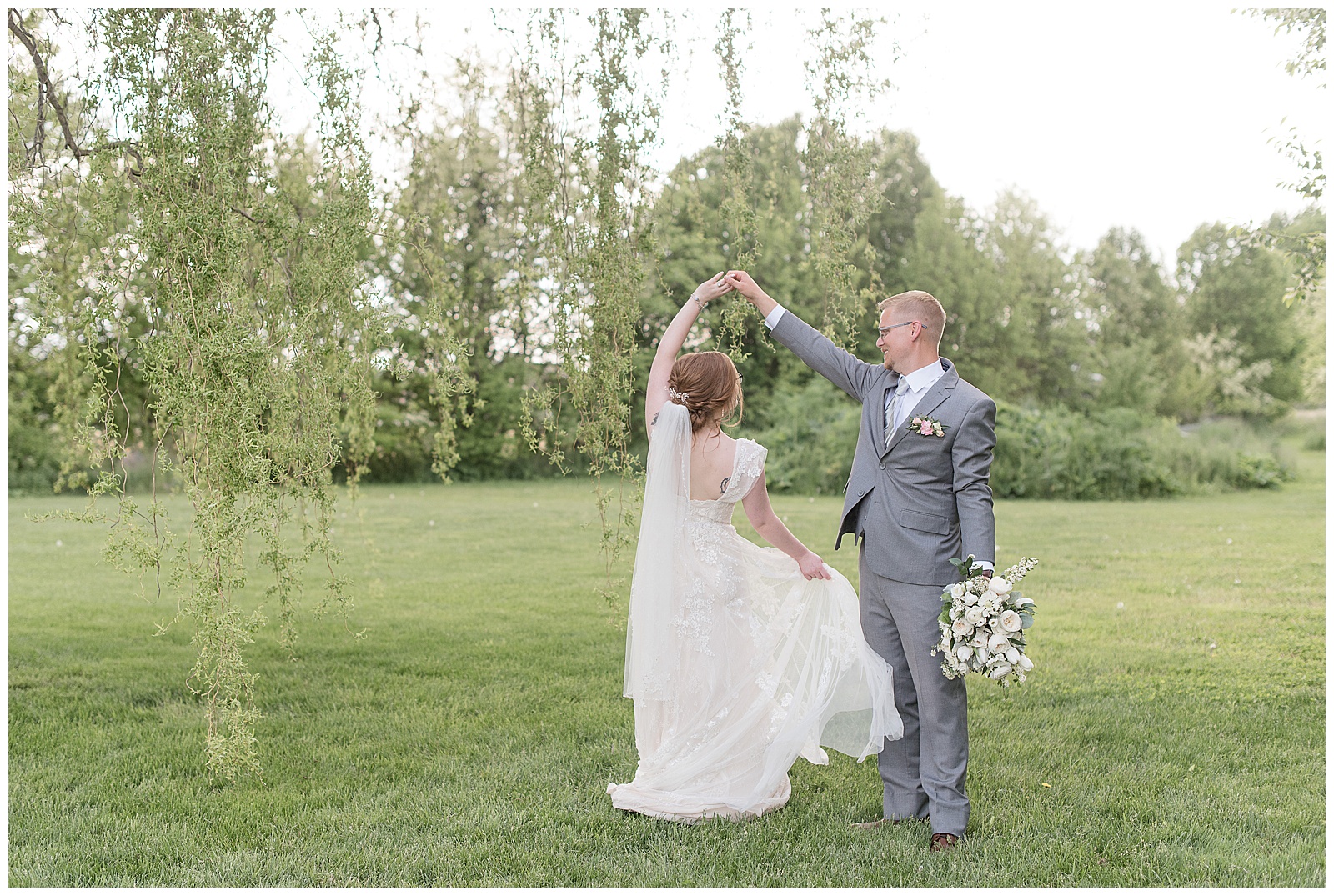 groom twirls bride under his right arm as he holds her bridal bouquet in his left hand