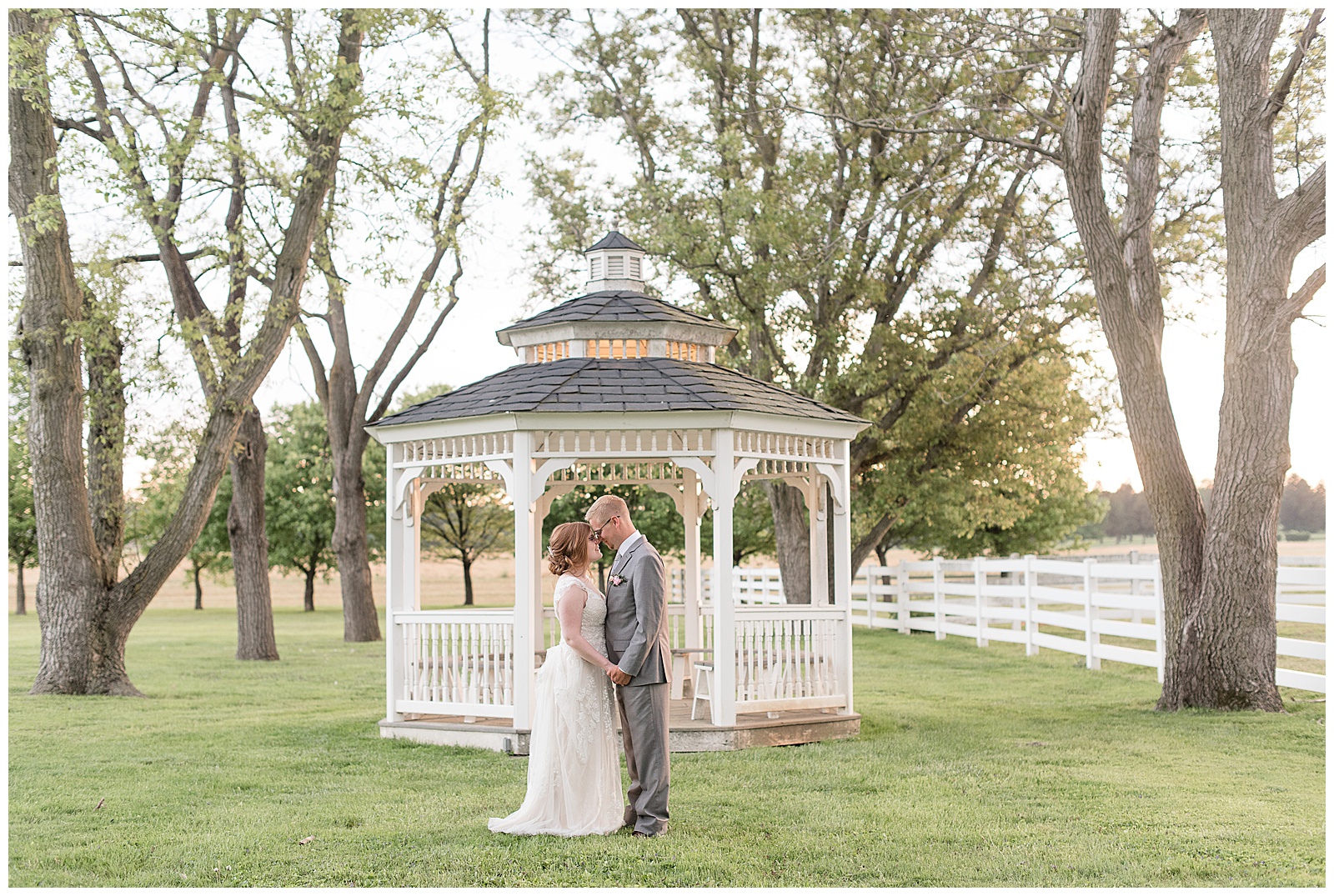 bride and groom kissing in front of white gazebo at the barn at silverstone