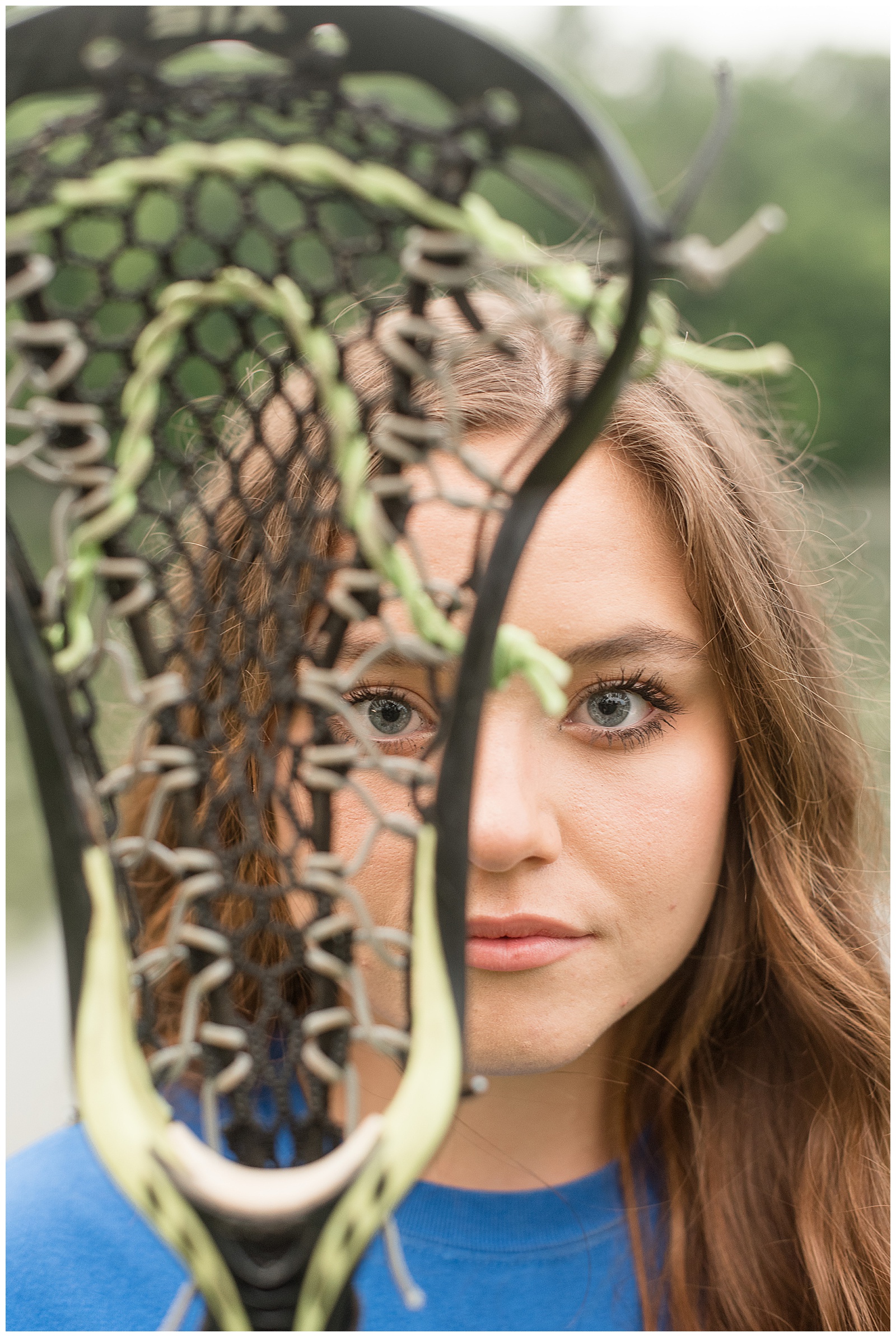 close up photo of lacrosse stick net with senior girl behind it looking through in lititz pennsylvania