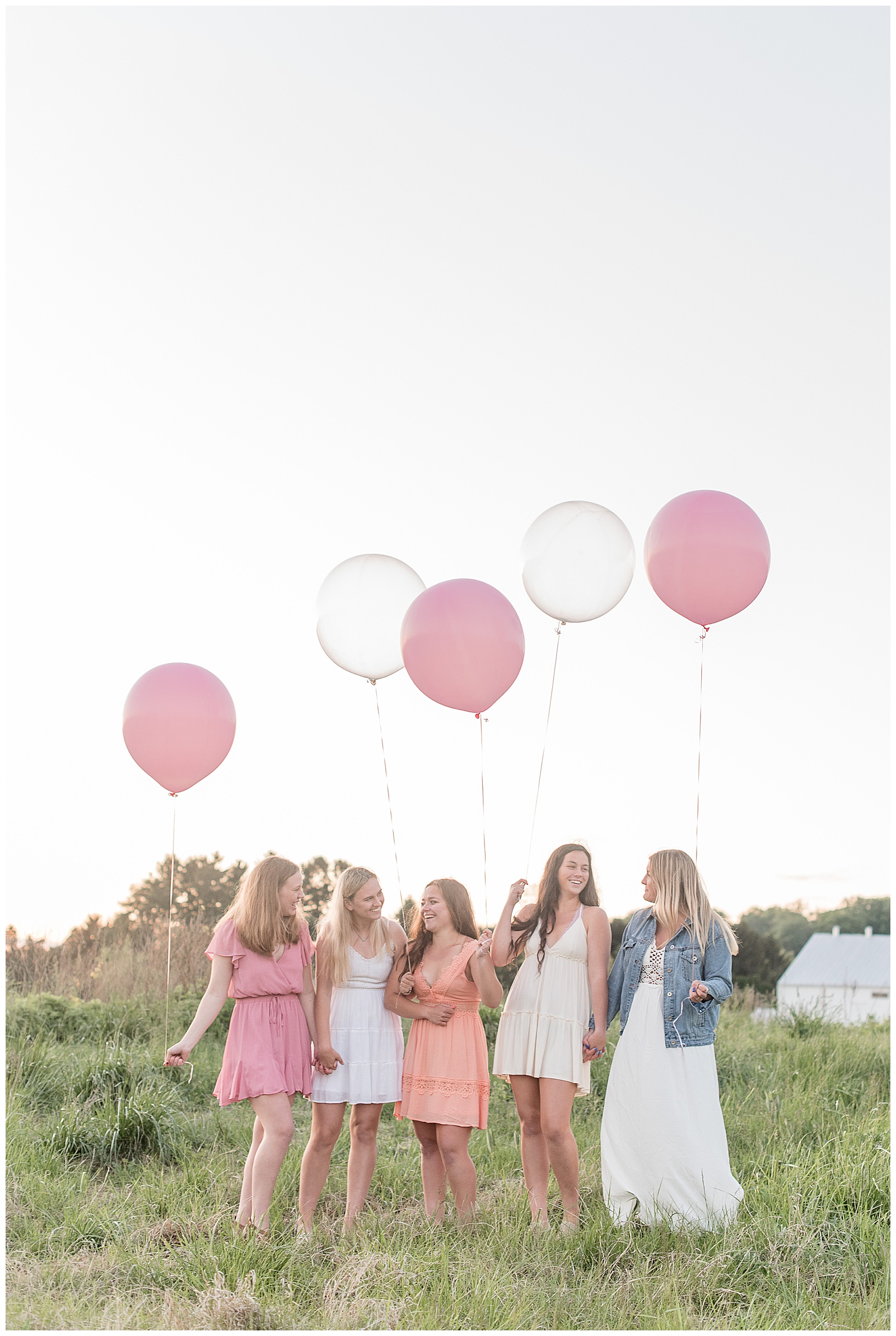 five senior girls standing close and laughing while each holding large balloon on sunny evening in lancaster pennsylvania
