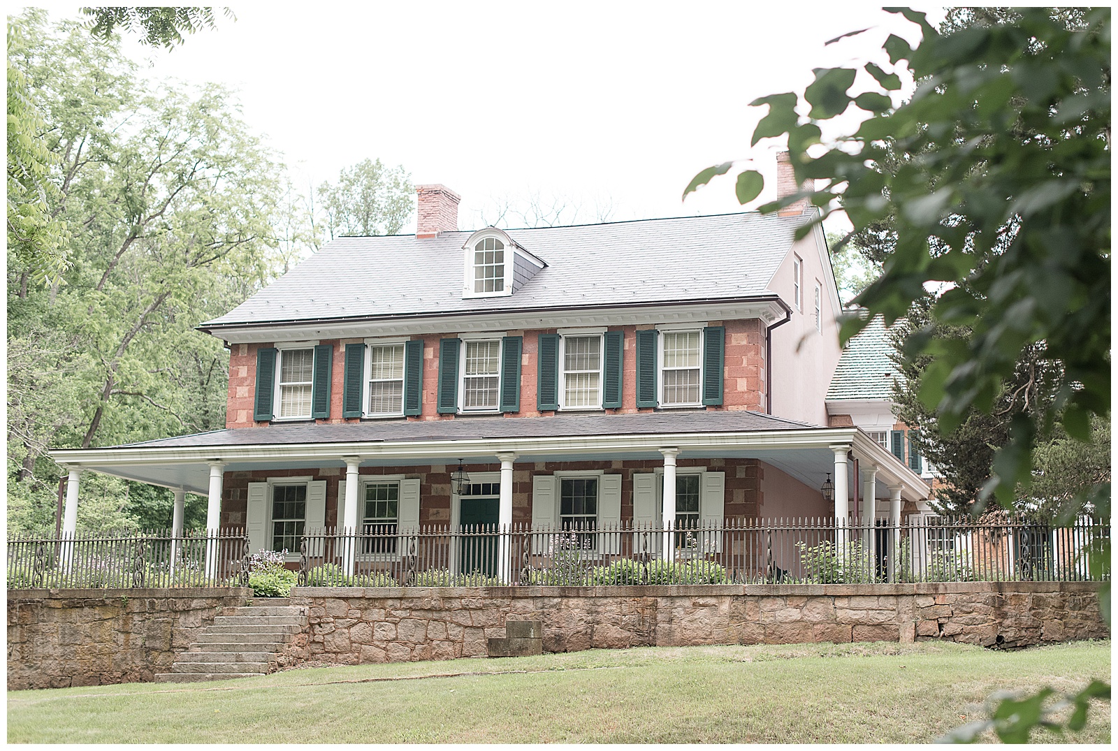 beautiful historic stone farmhouse with dark green and white shutters and wrap-around front porch at elizabeth furnace