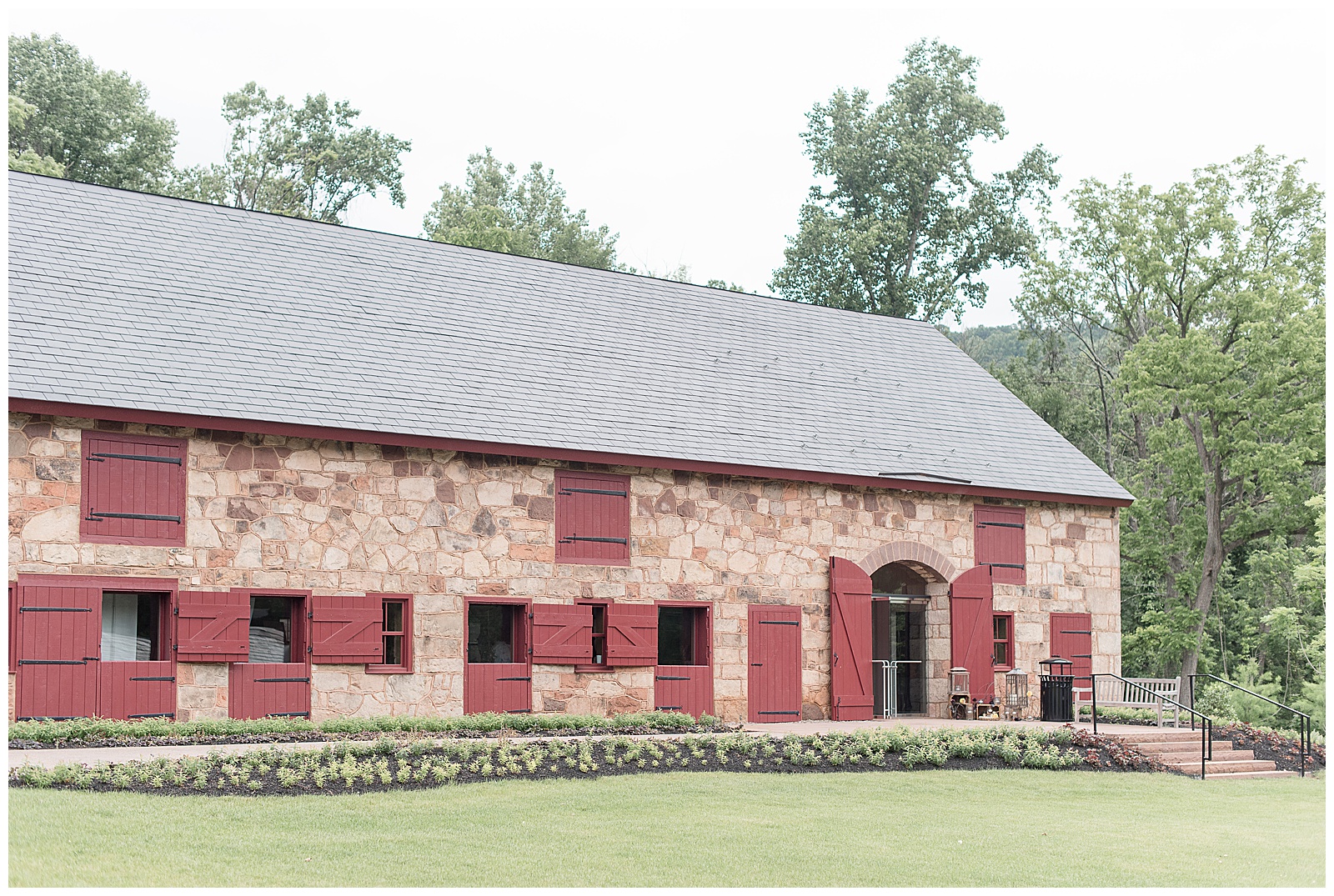 beautiful historic stone barn with maroon barn doors and manicured lawn at elizabeth furnace