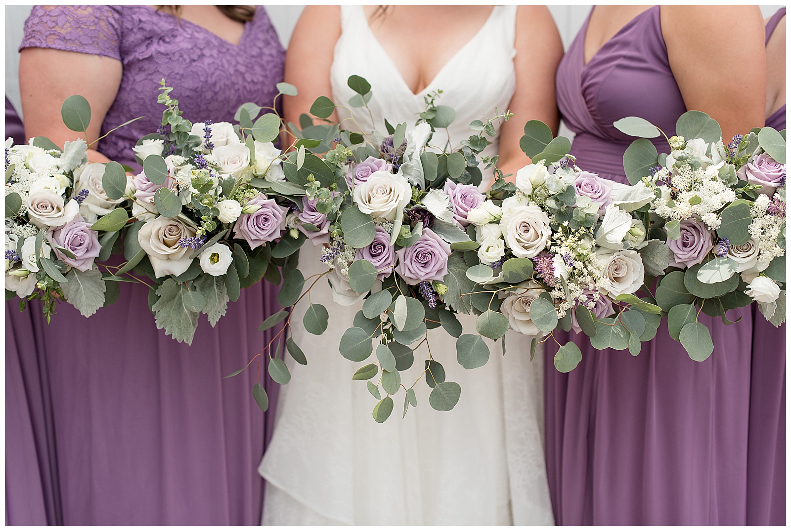 close up photo of bride and two bridesmaids holding white and lavender rose with eucalyptus bouquets at lakefield weddings