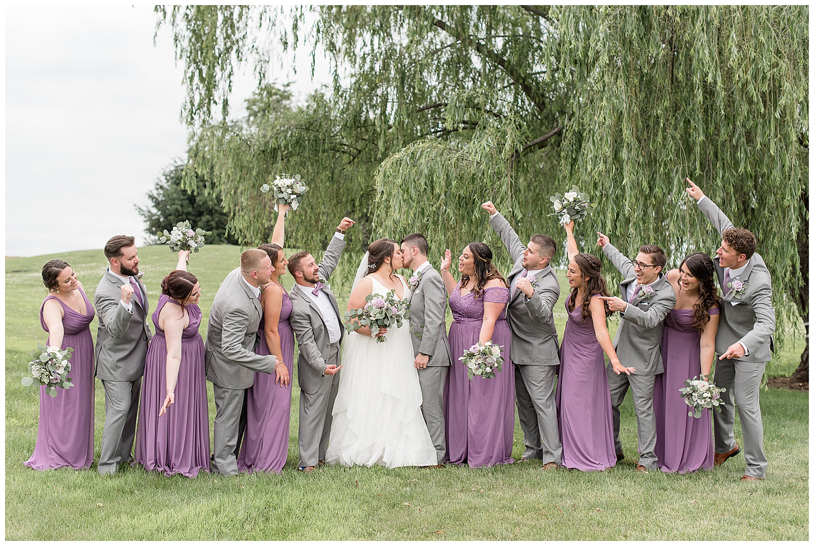 couple kissing surrounded by bridal party with their arms raised cheering for them in lancaster, pennsylvania