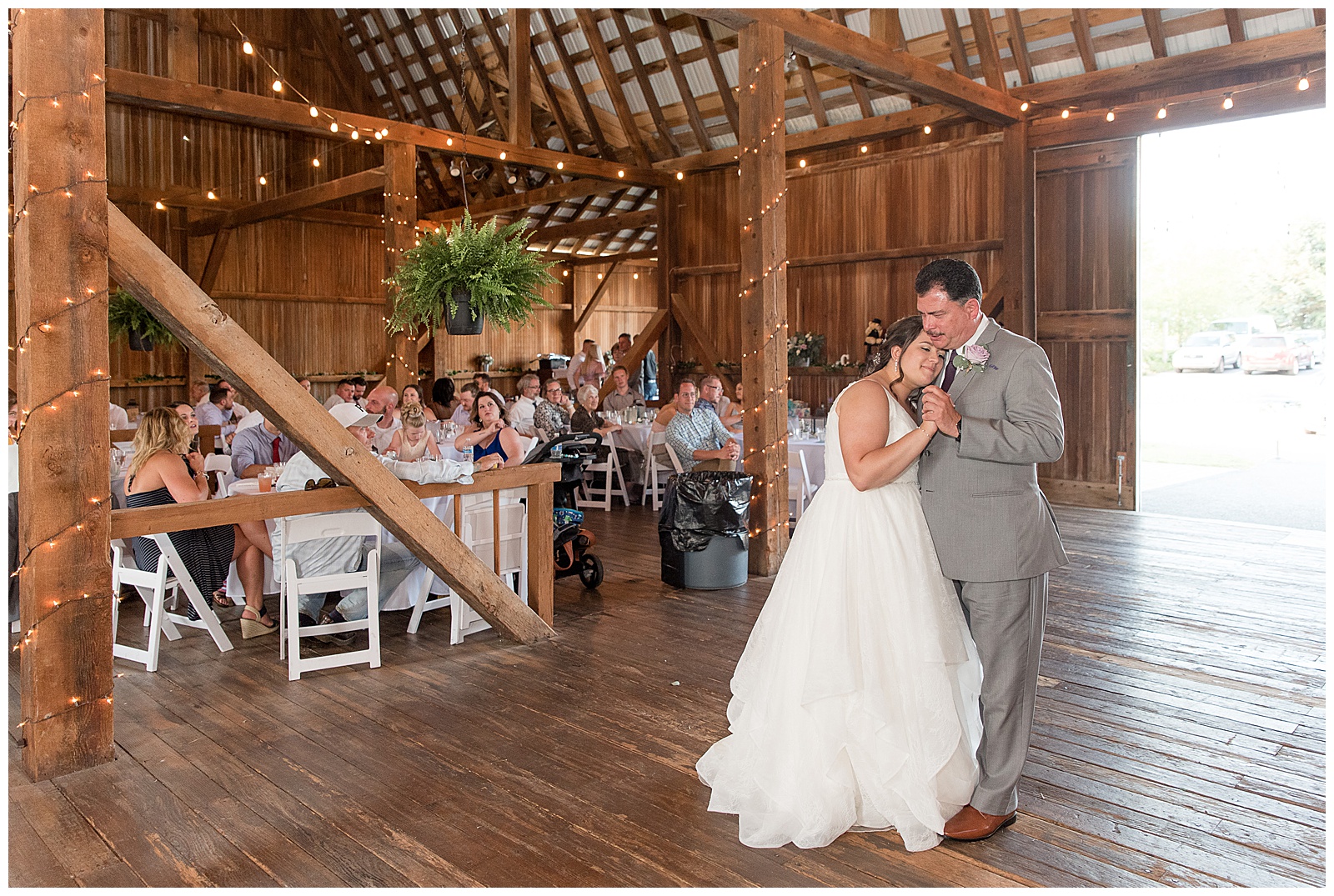 bride resting her head on her father's shoulder as they do the father-daughter dance inside barn venue in lancaster, pennsylvania