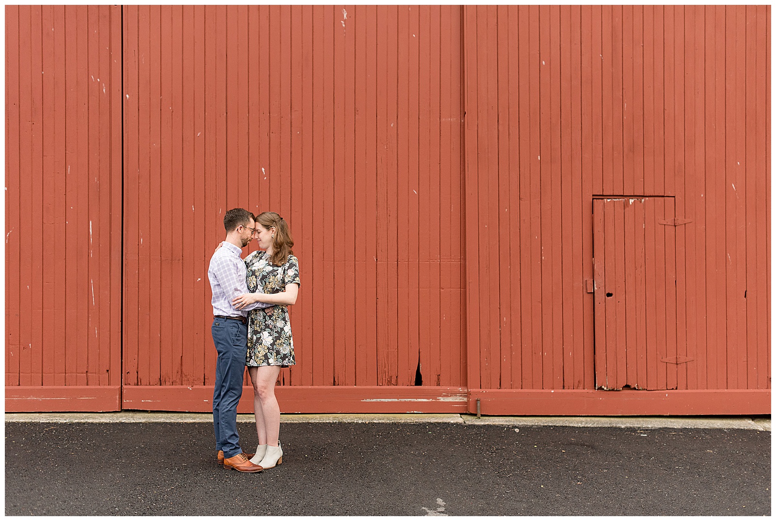 couple standing close resting foreheads together holding arms by large red barn door in mechanicsburg, pennsylvania