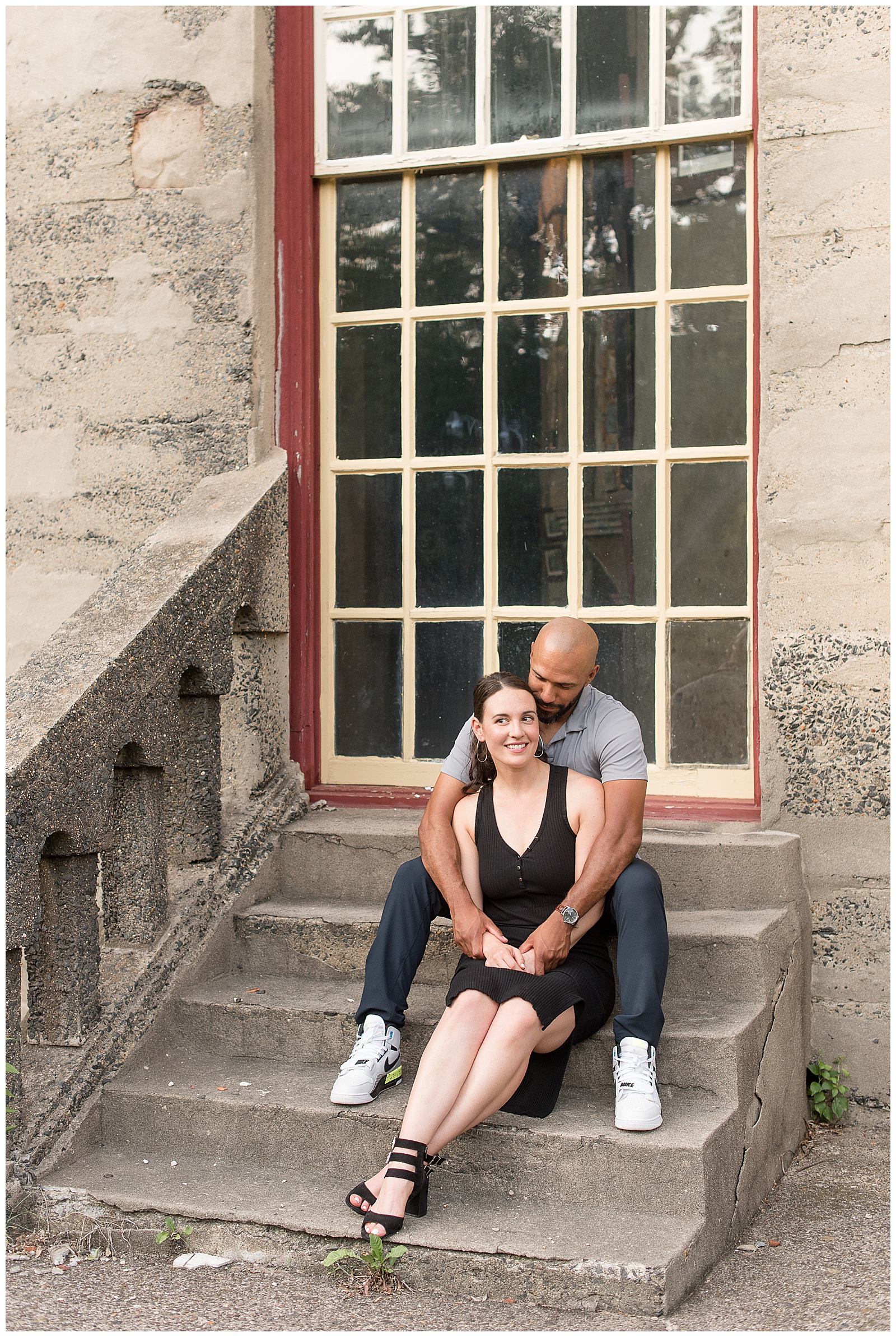 couple sitting on concrete steps of fonthill castle as guy kisses girl from behind