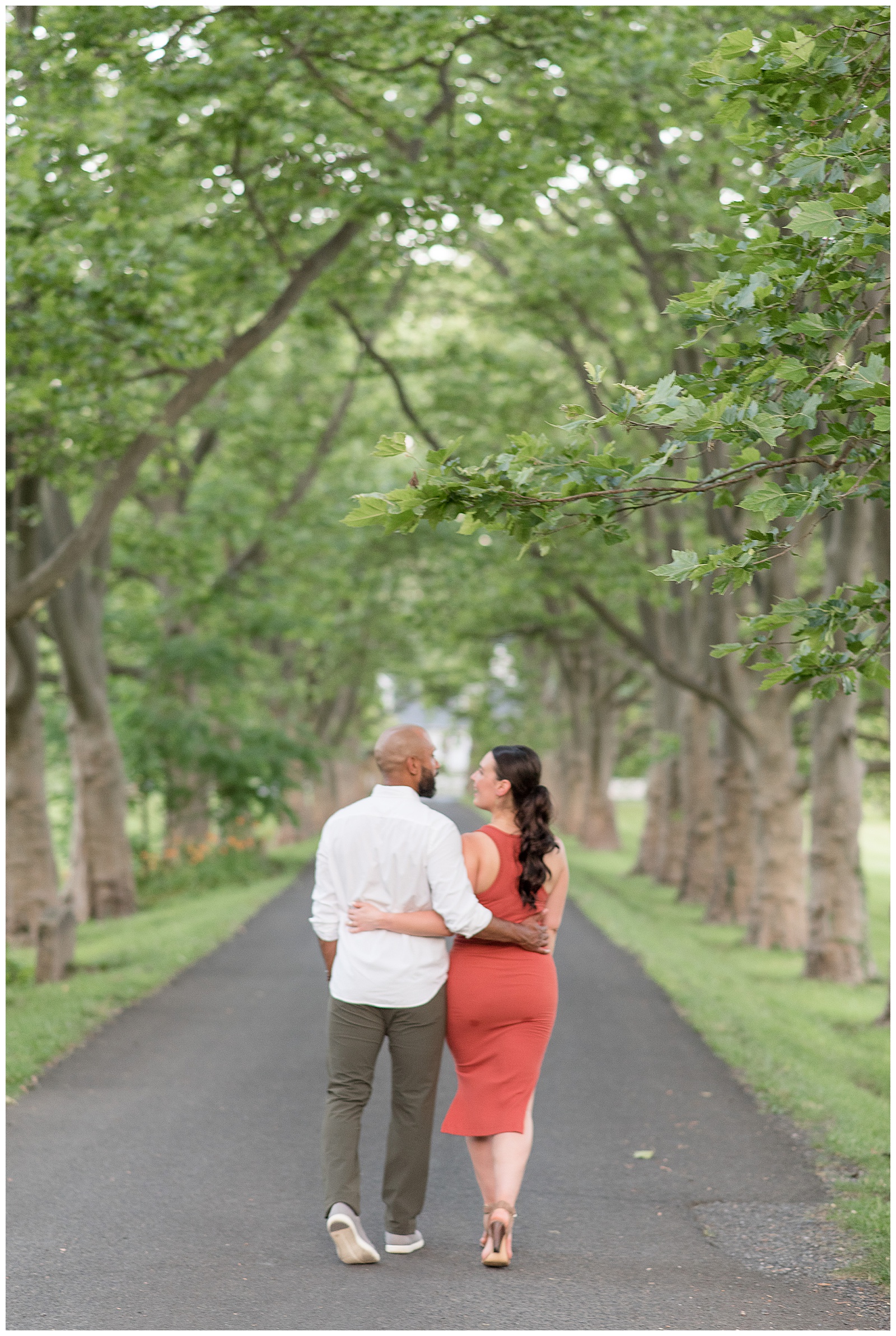 couple walking away from camera with their arms around each other along path in doylestown pennsylvania