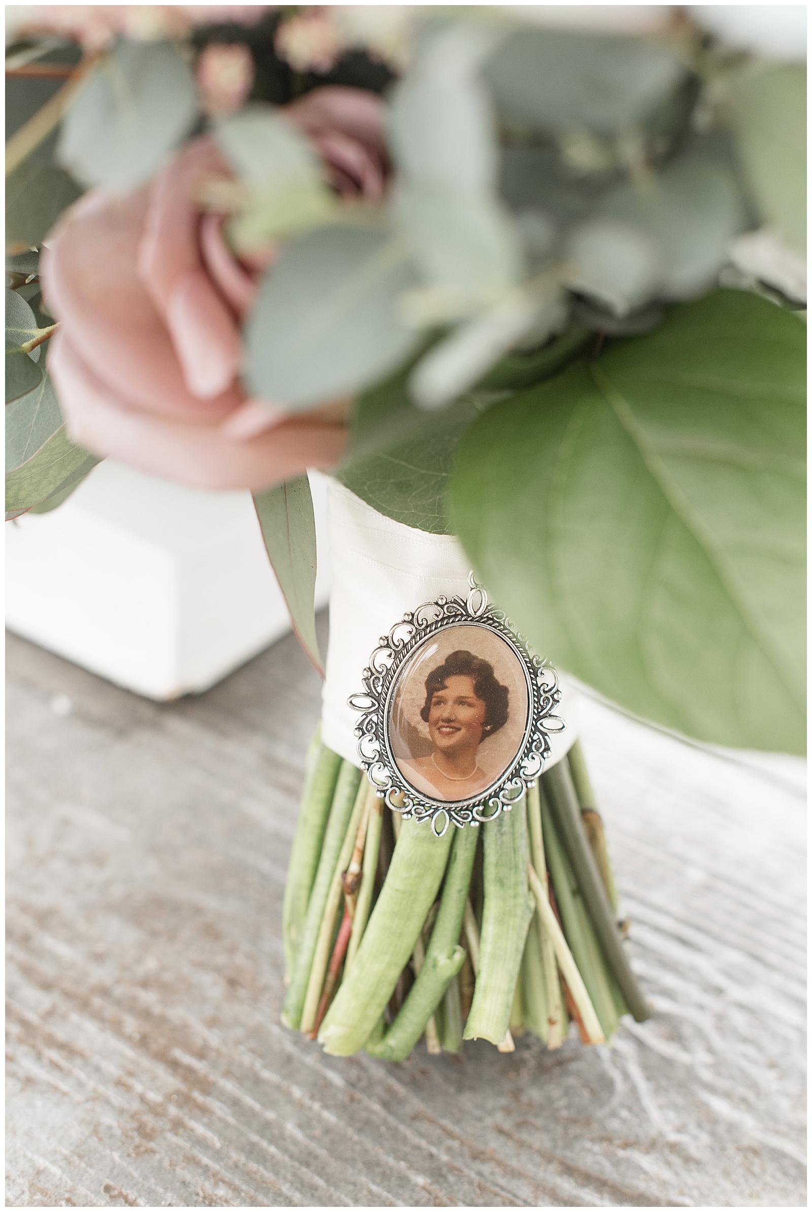 close up of bride's blush and white floral bouquet with charm of her deceased grandmother attached to it