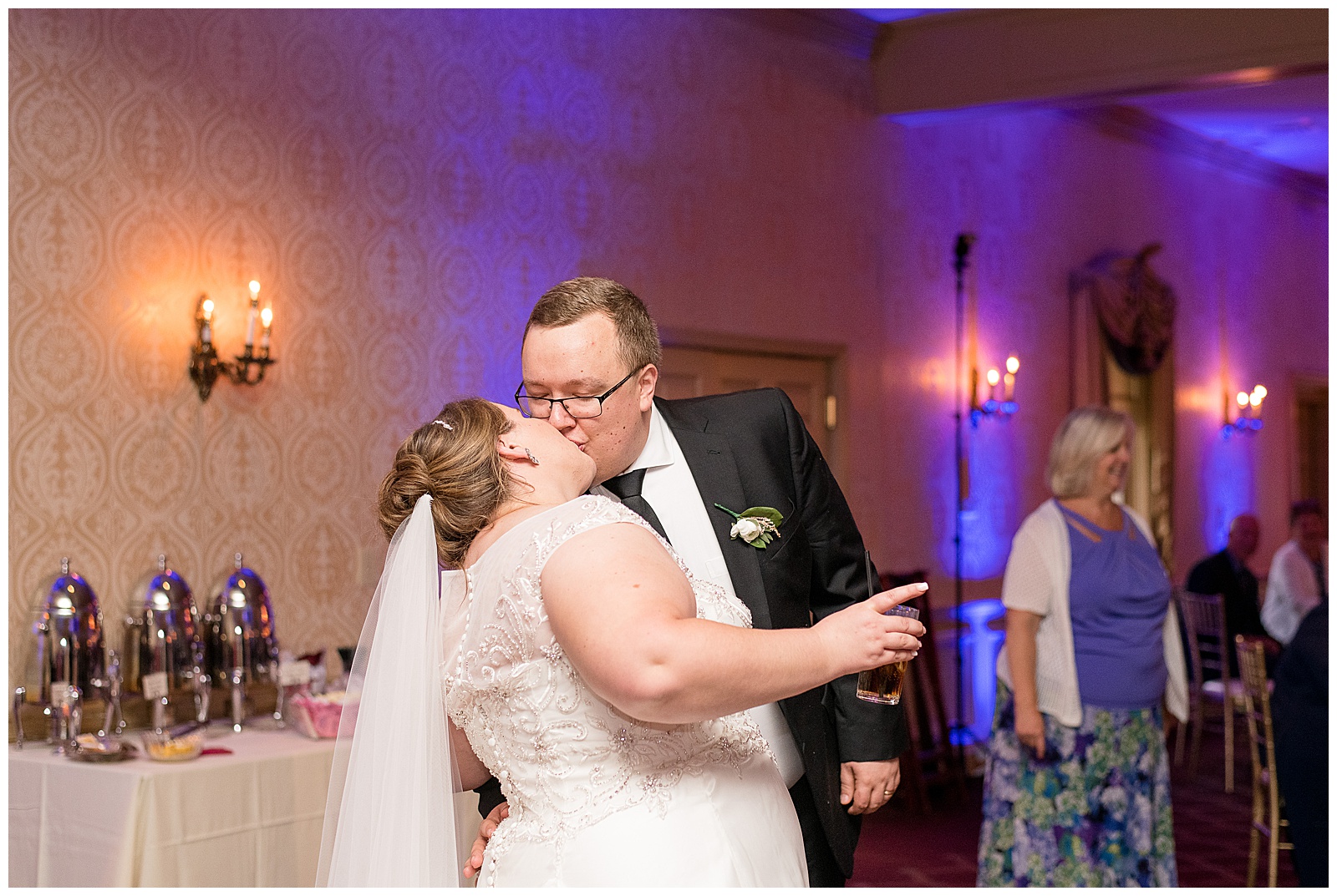 groom kissing bride on dance floor during wedding reception with colorful lights behind them in strasburg pennsylvania
