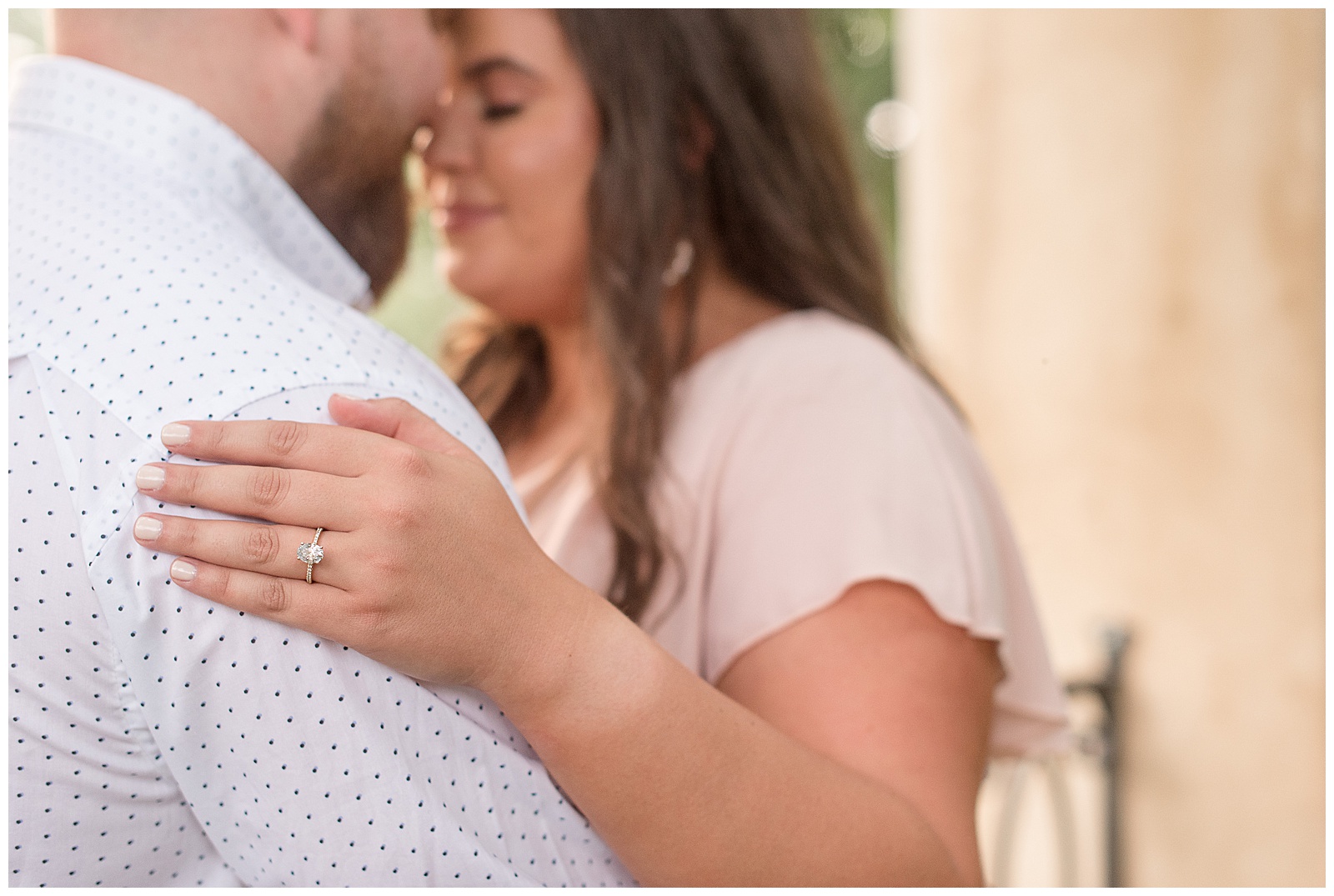 couple hugging and resting foreheads together with a close-up photo of diamond engagement ring resting on guy's right shoulder in lancaster pennsylvania