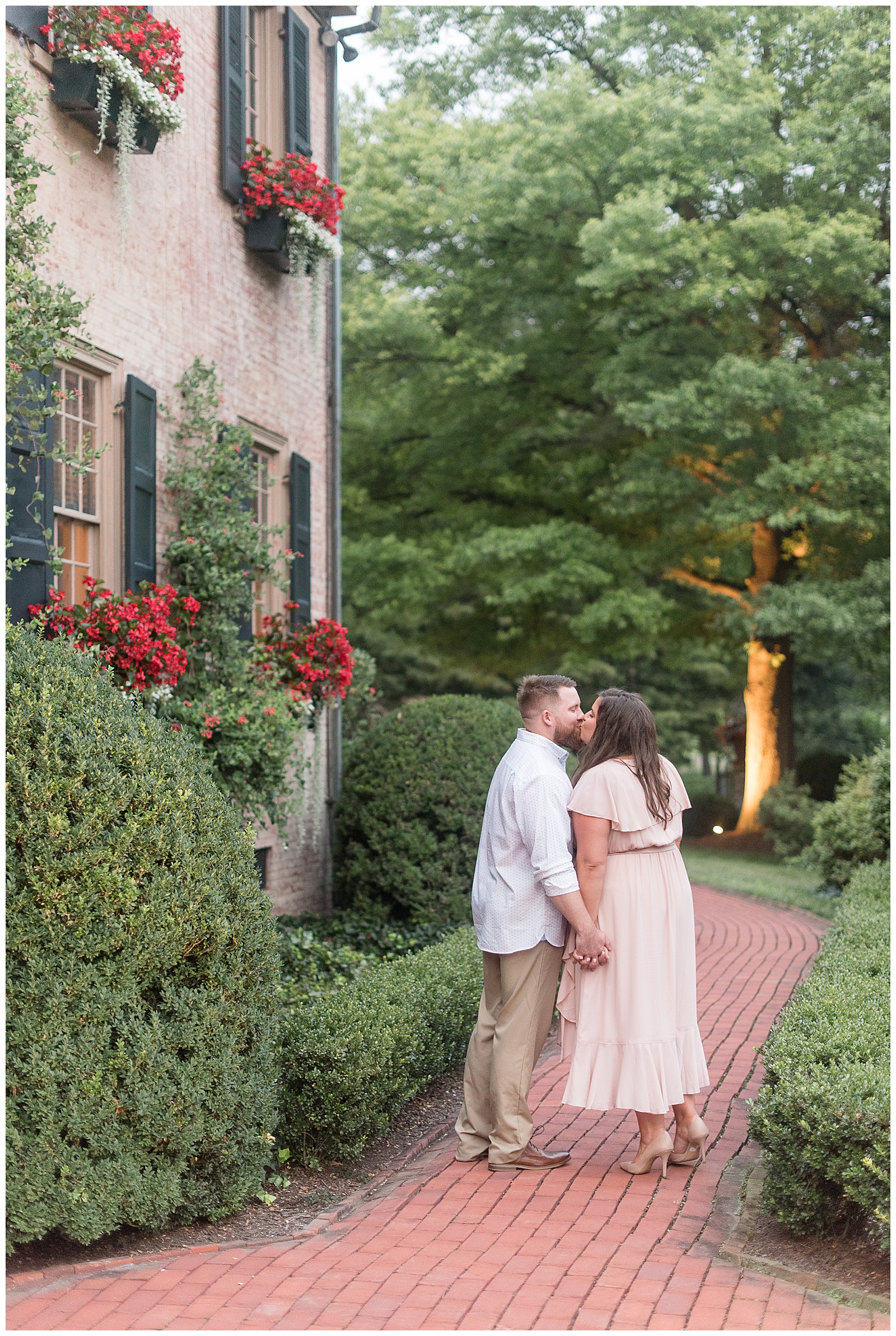 couple kissing with backs toward camera along brick pathway of beautiful home at conestoga house and gardens