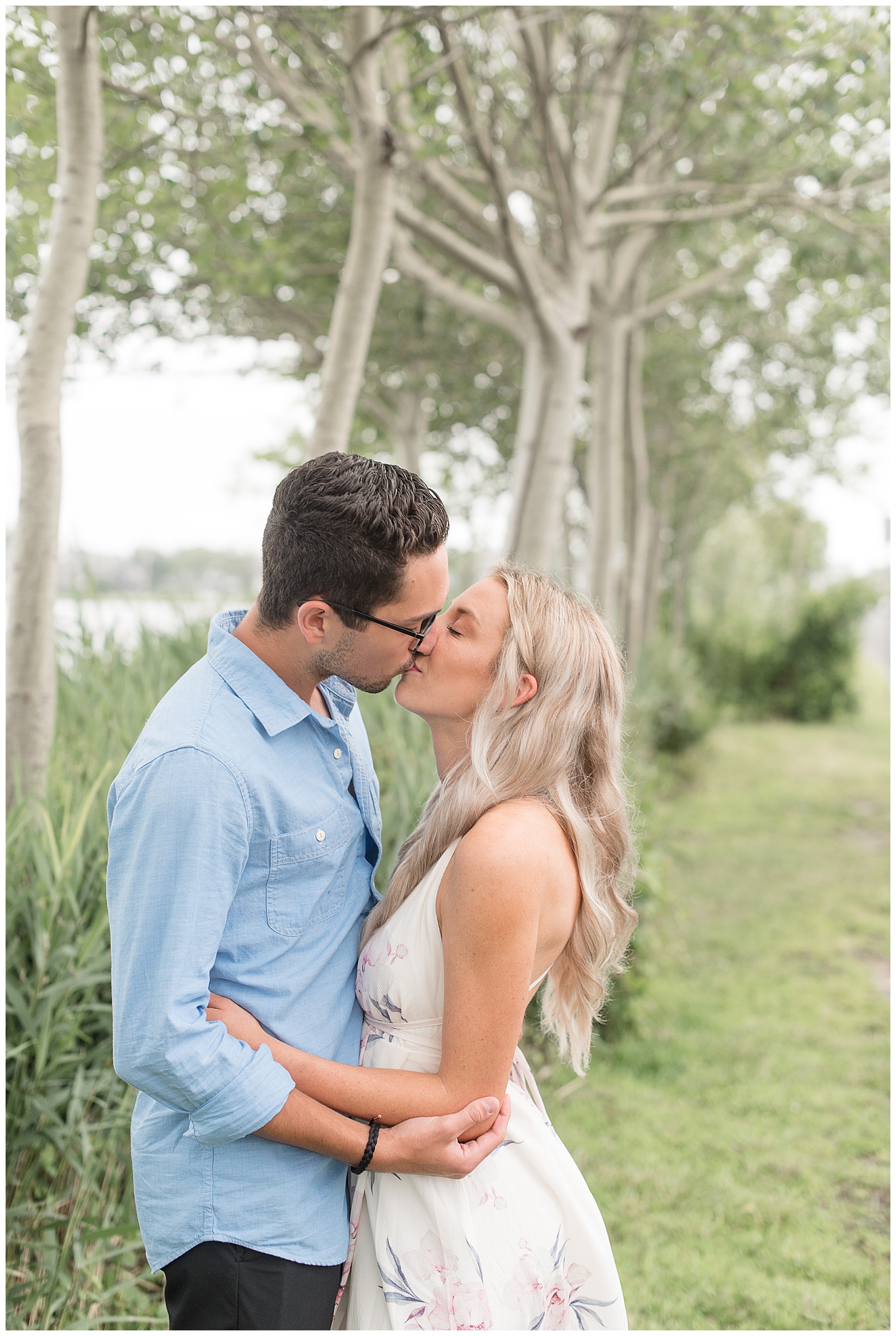couple kissing with arms wrapped around each other along tall grasses by the bay in new jersey