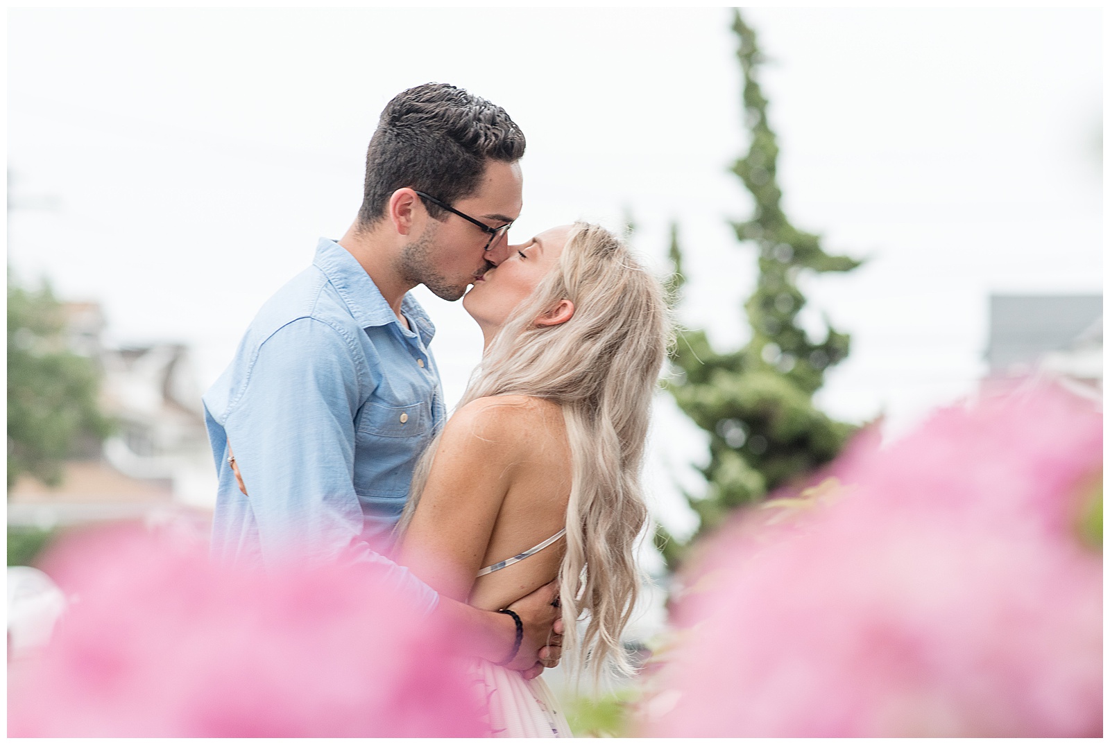 guy wearing light blue dress shirt kissing girl in strappy floral dress in bayhead new jersey