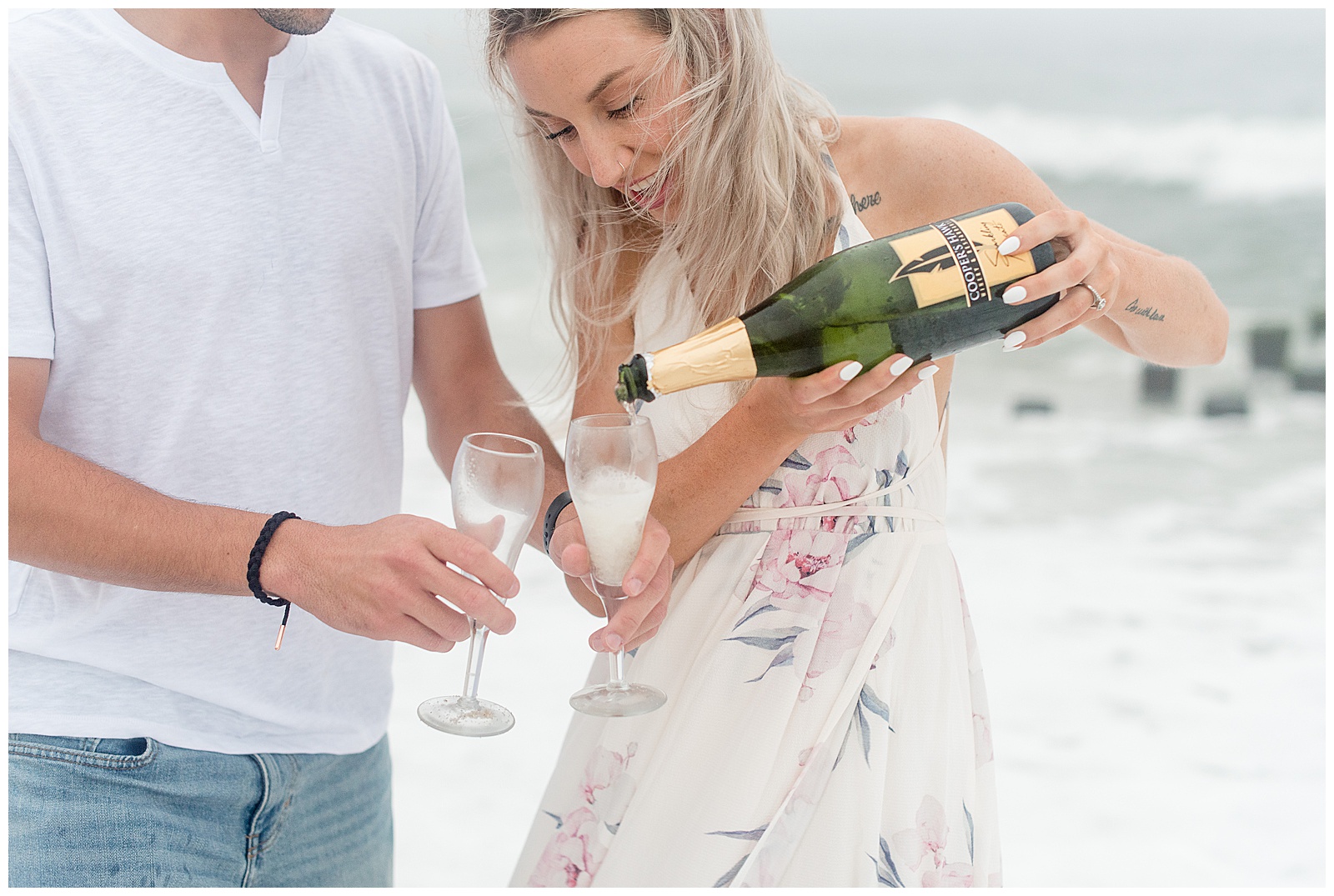 bride-to-be pouring champagne into two glasses along ocean in bayhead new jersey
