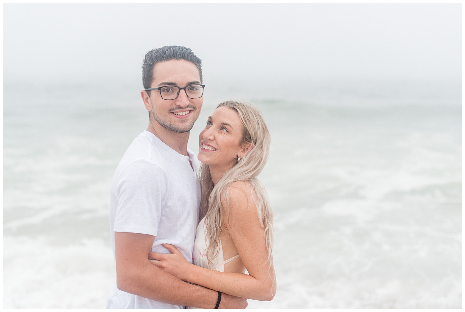 girl smiling looking up at guy as he smiles and looks at the camera with ocean behind them in new jersey