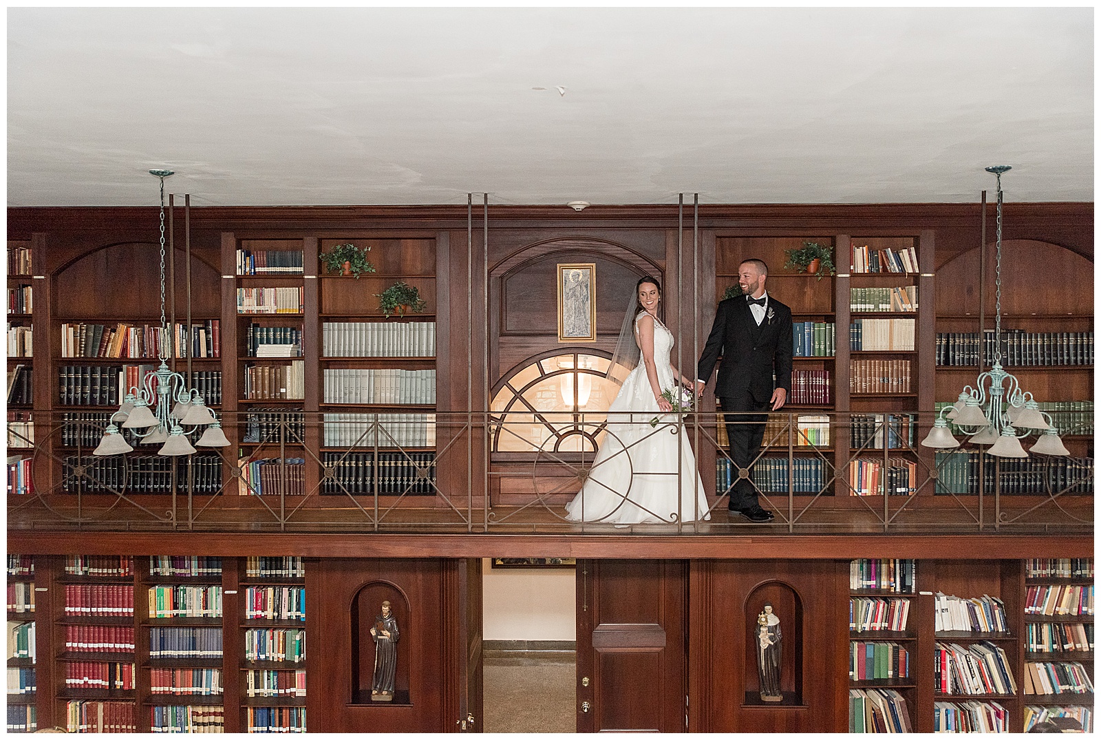 bride and groom walking along bookcases in the library at the Shrine of Saint Anthony