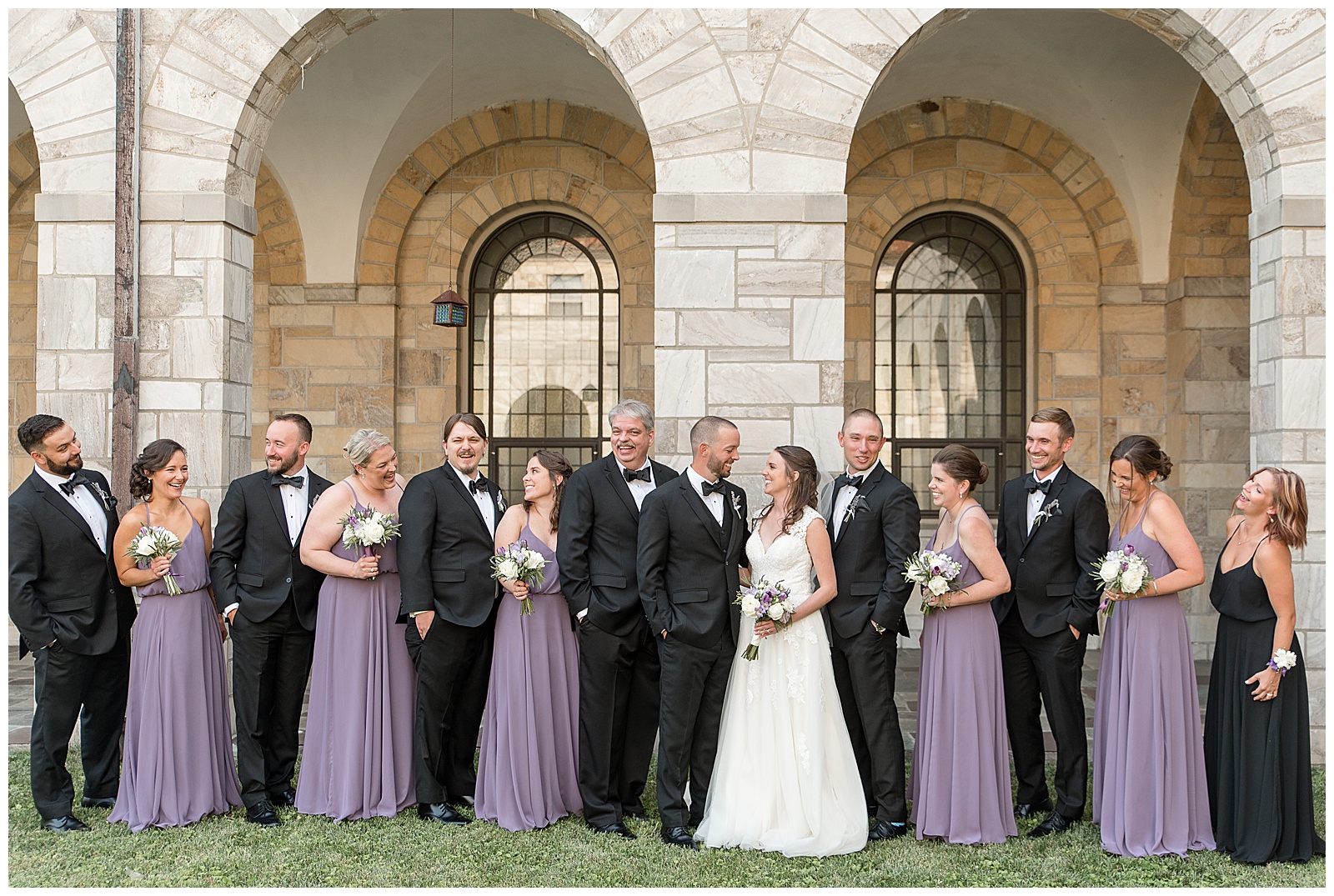 bridal party laughing together in front of stone arches