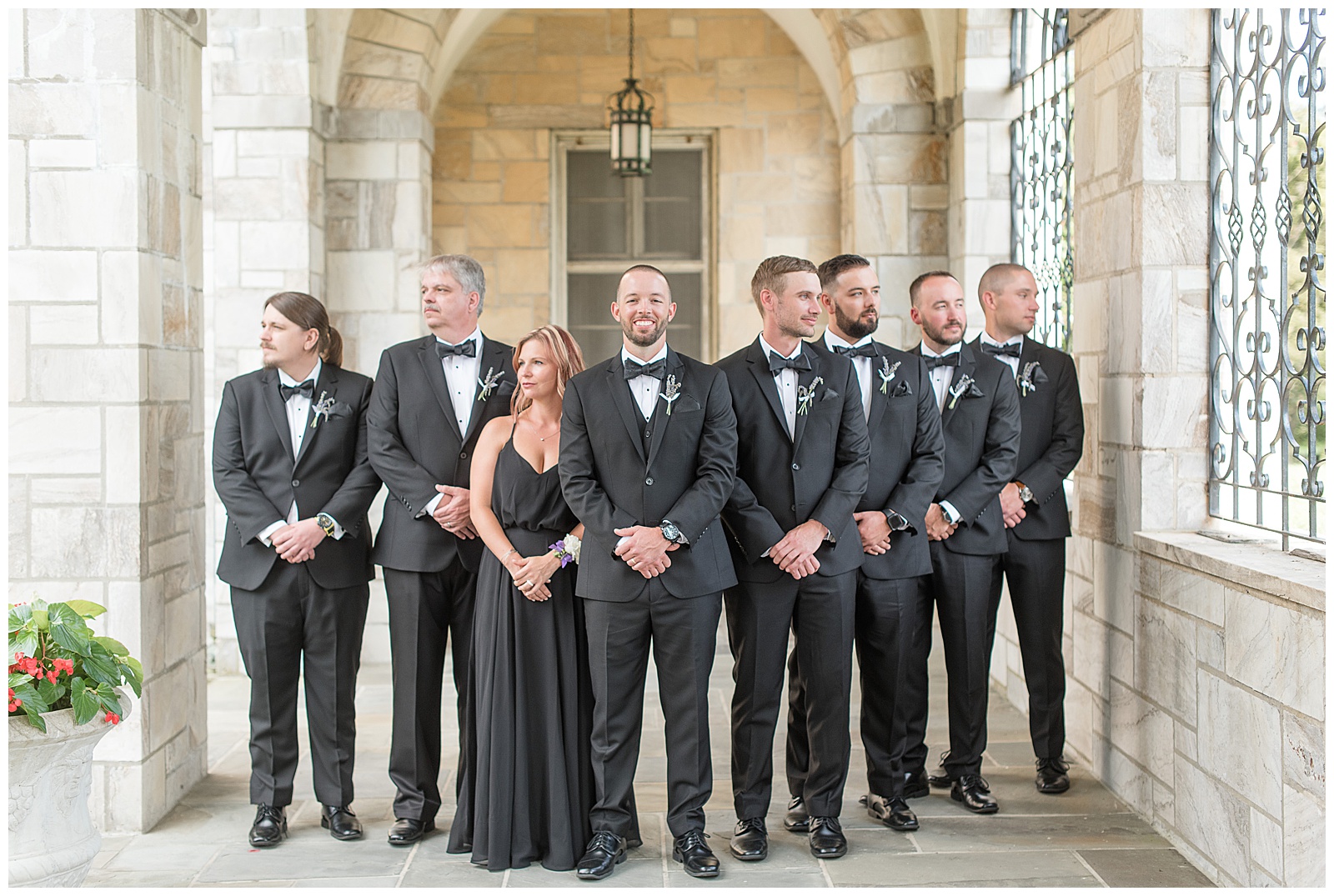 groom looking at camera while bridal party looks in either direction off camera with hands crossed in front