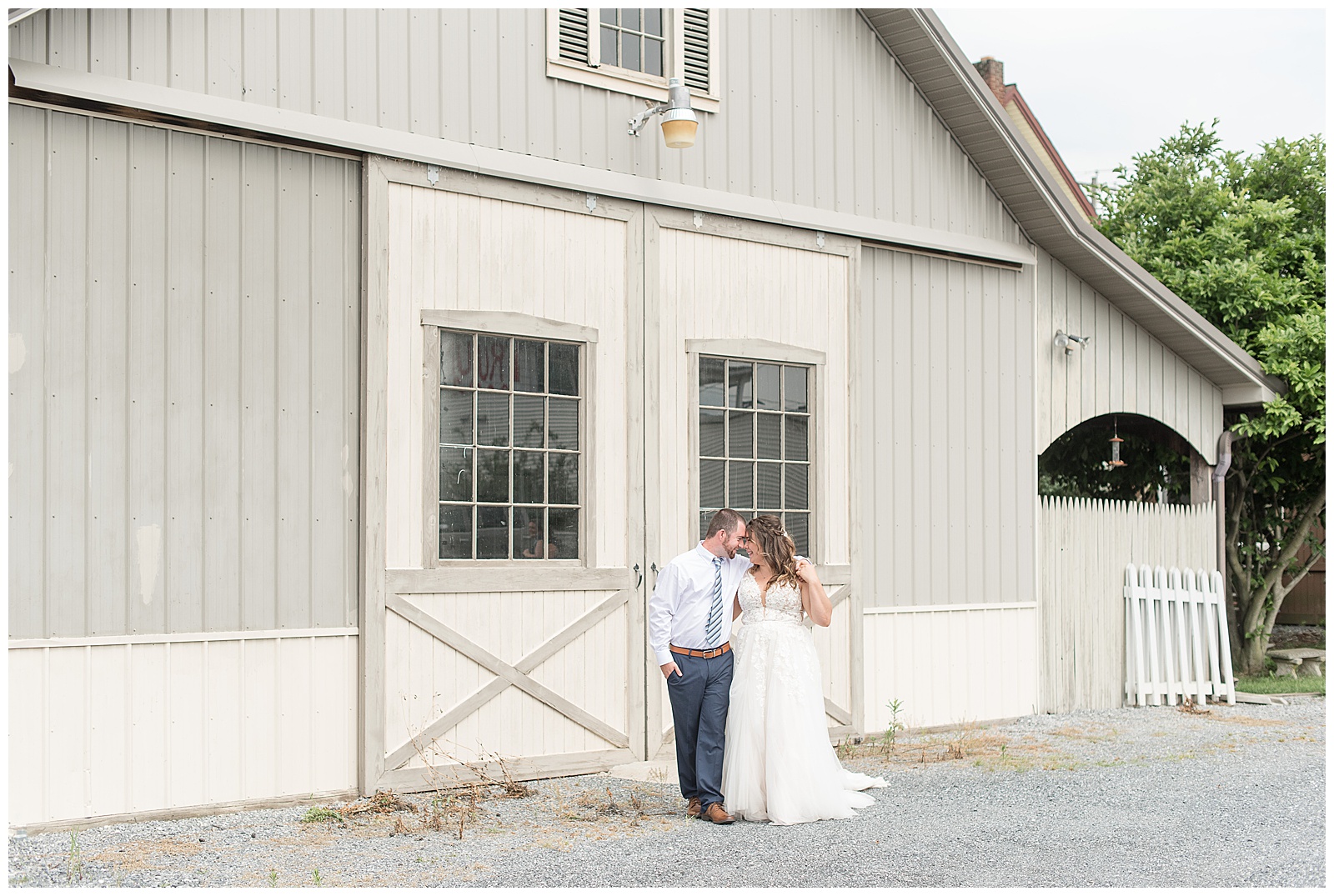 bride and groom walking in front of white barn doors