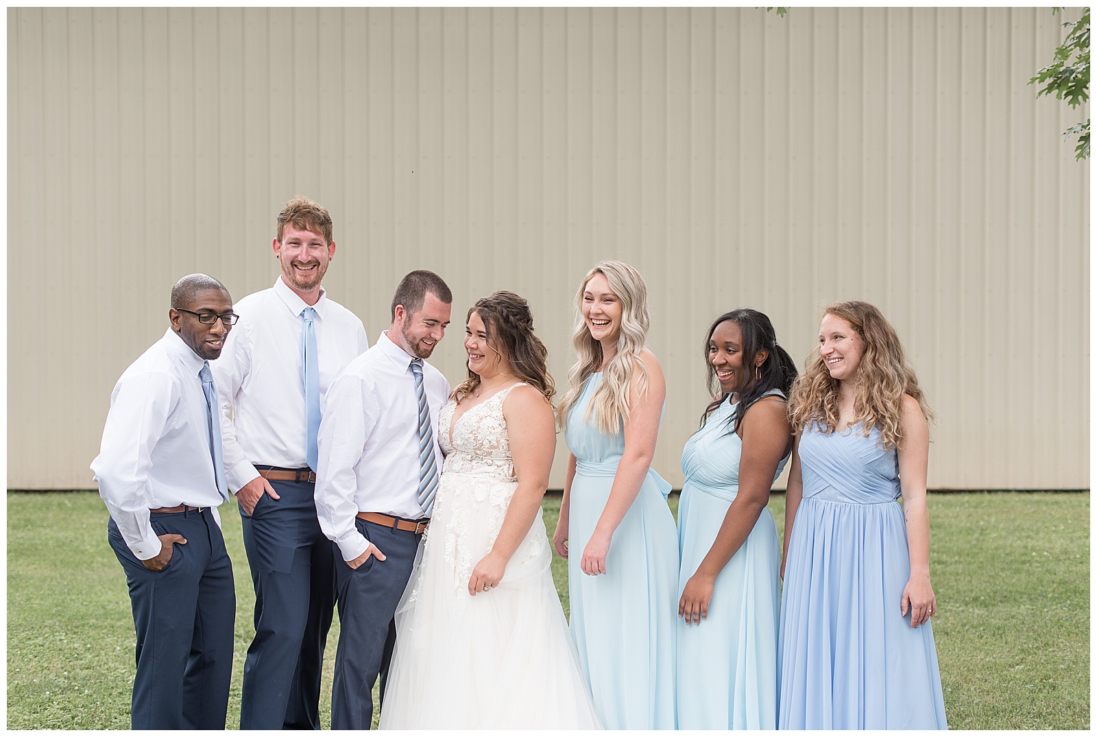 full bridal party in shades of blue laughing at each other
