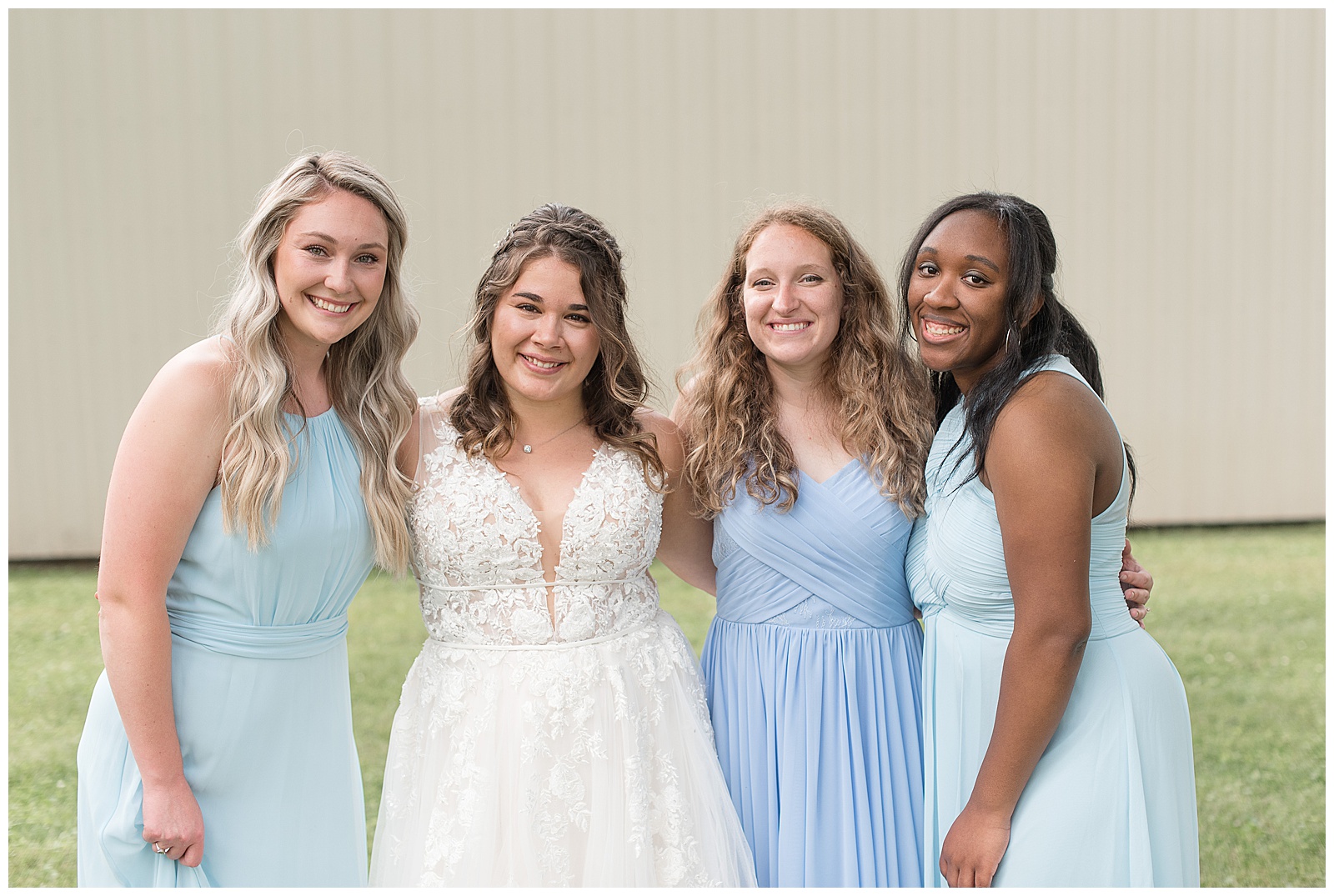 bridesmaids in shades of blue dresses smiling at camera