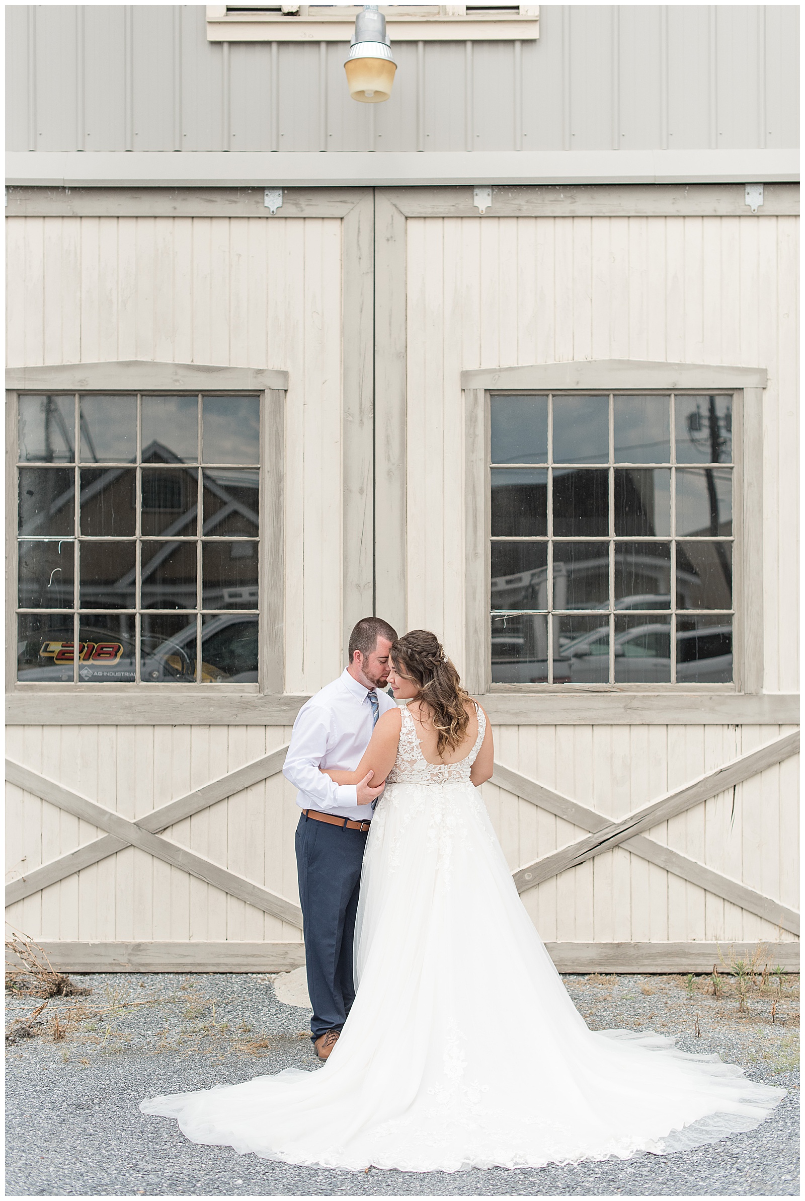 bride and groom resting foreheads together in front of white barn doors