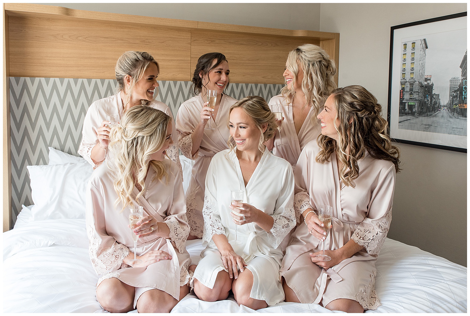 bride in white robe surrounded by five bridesmaids in peach colored robes in bridal suite of barn at silverstone