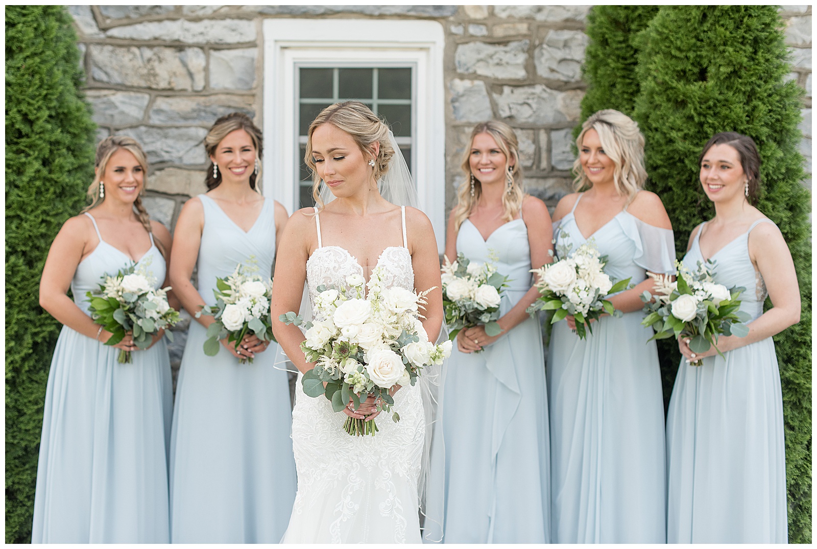 bride standing in front of bridesmaids looking down as they look at her all holding bouquets in lancaster pennsylvania