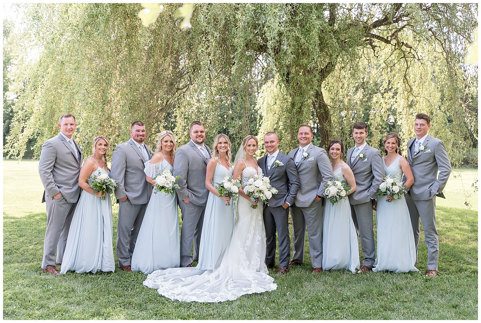 bride and groom surrounded by bridal party under willow tree at the barn at silverstone