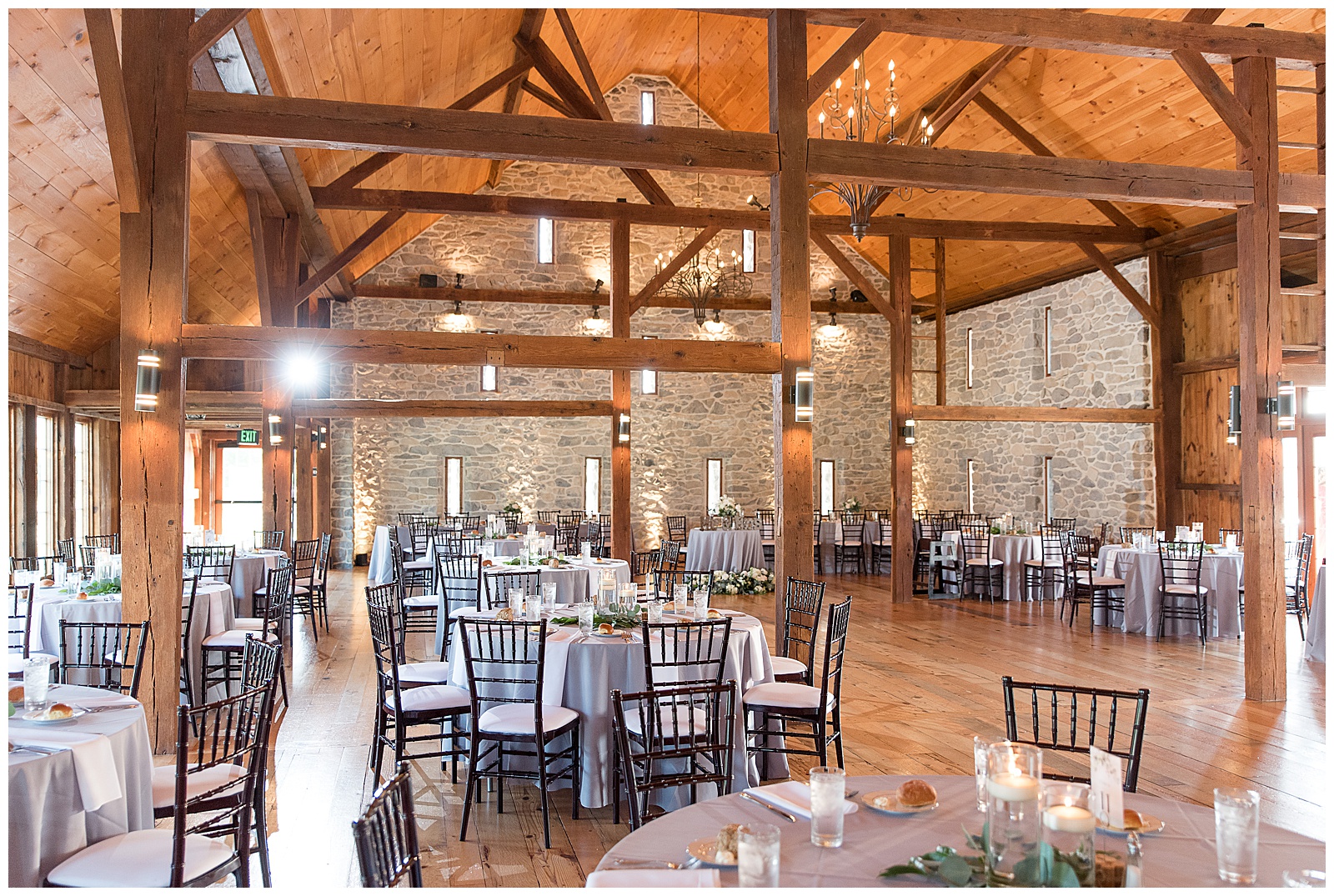 wedding reception beautifully decorated inside gorgeous barn with tables with white linens and wooden chairs at the barn at silverstone