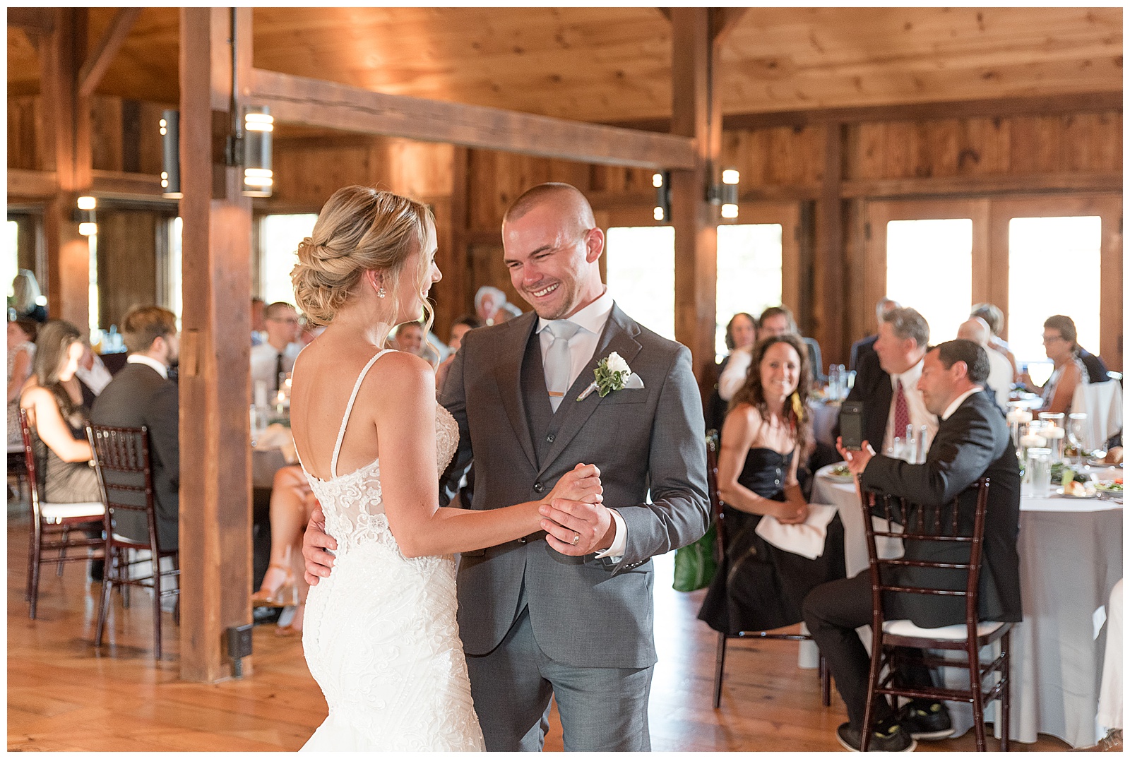 bride and groom dance for the first time as husband and wife inside barn during reception at the barn at silverstone