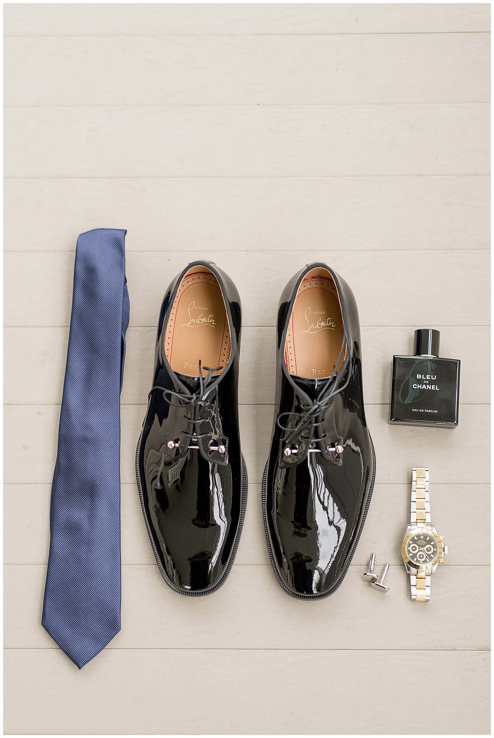 groom's shoes, navy blue tie, cologne, cuff links and watch displayed on off-white wooden floor boards at Antrim 1844