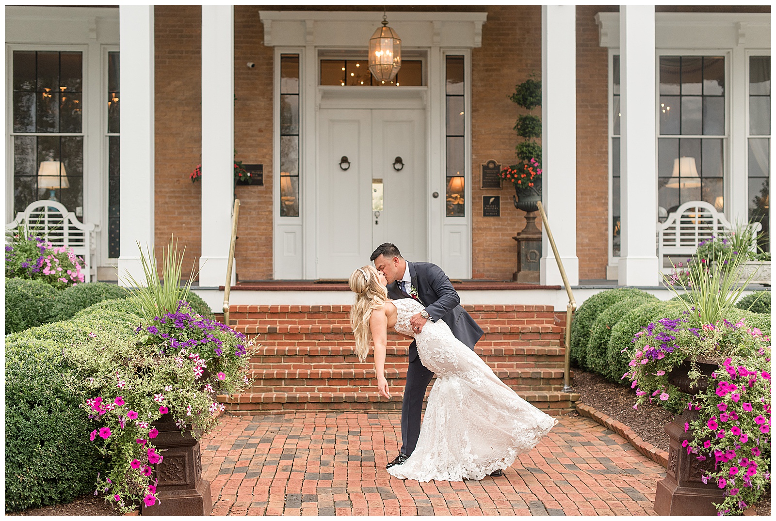 groom dips bride back and kisses her on brick walkway in front of historic home at Antrim 1844 in Maryland